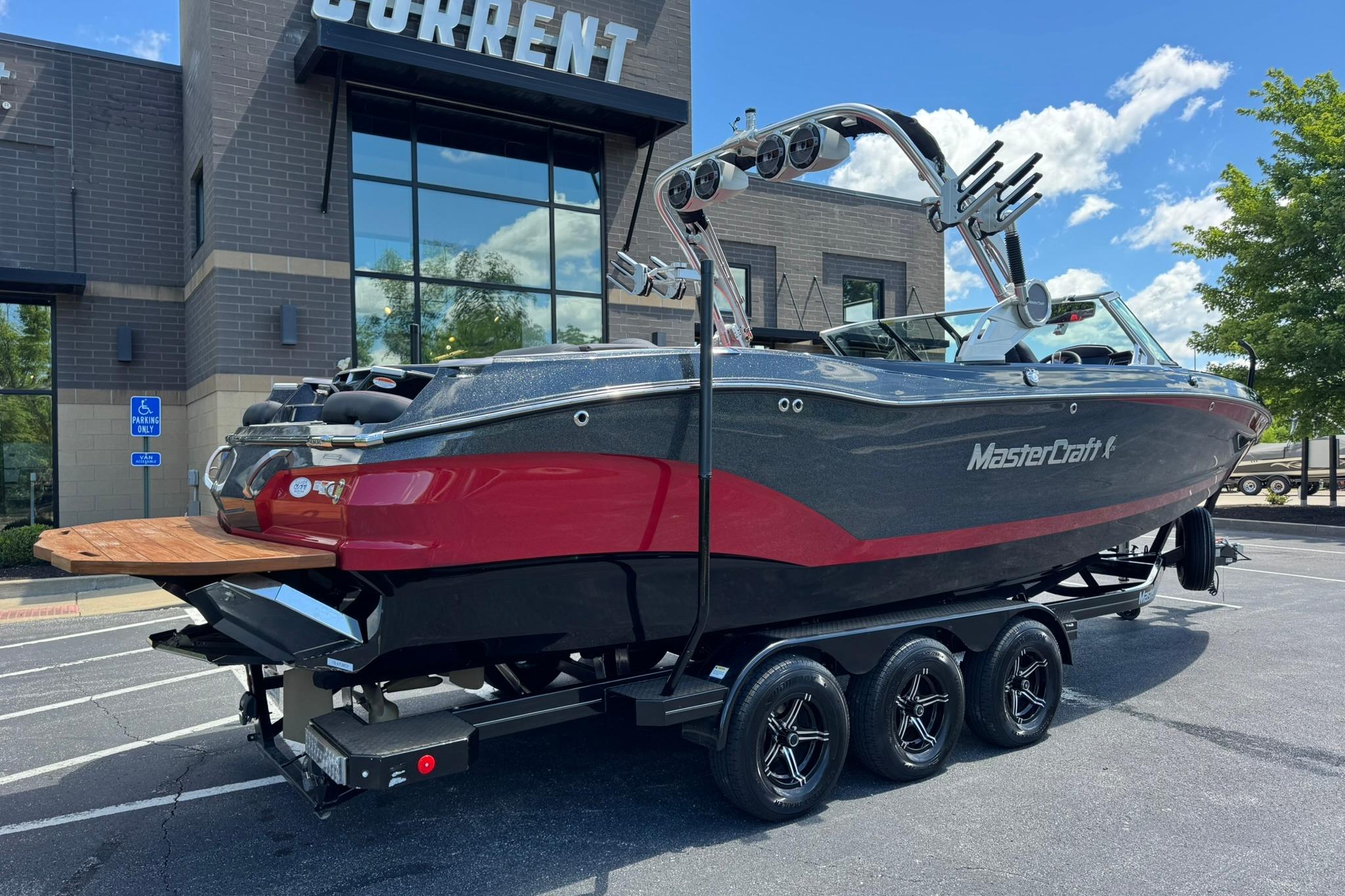 2021 MasterCraft X26 boat on trailer, parked outside a modern building.