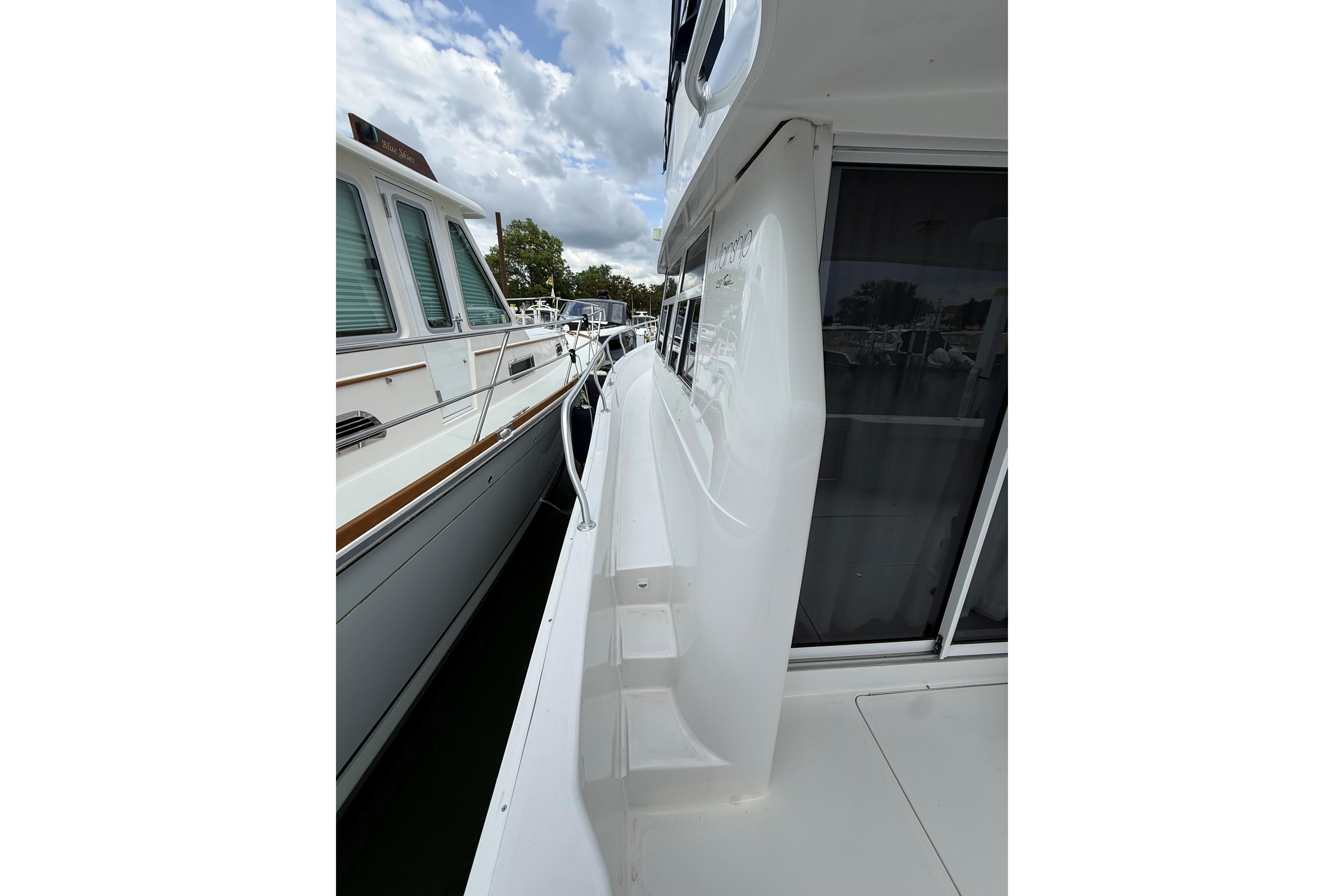 1999 Mainship 350 Trawler side deck view with railing and windows.