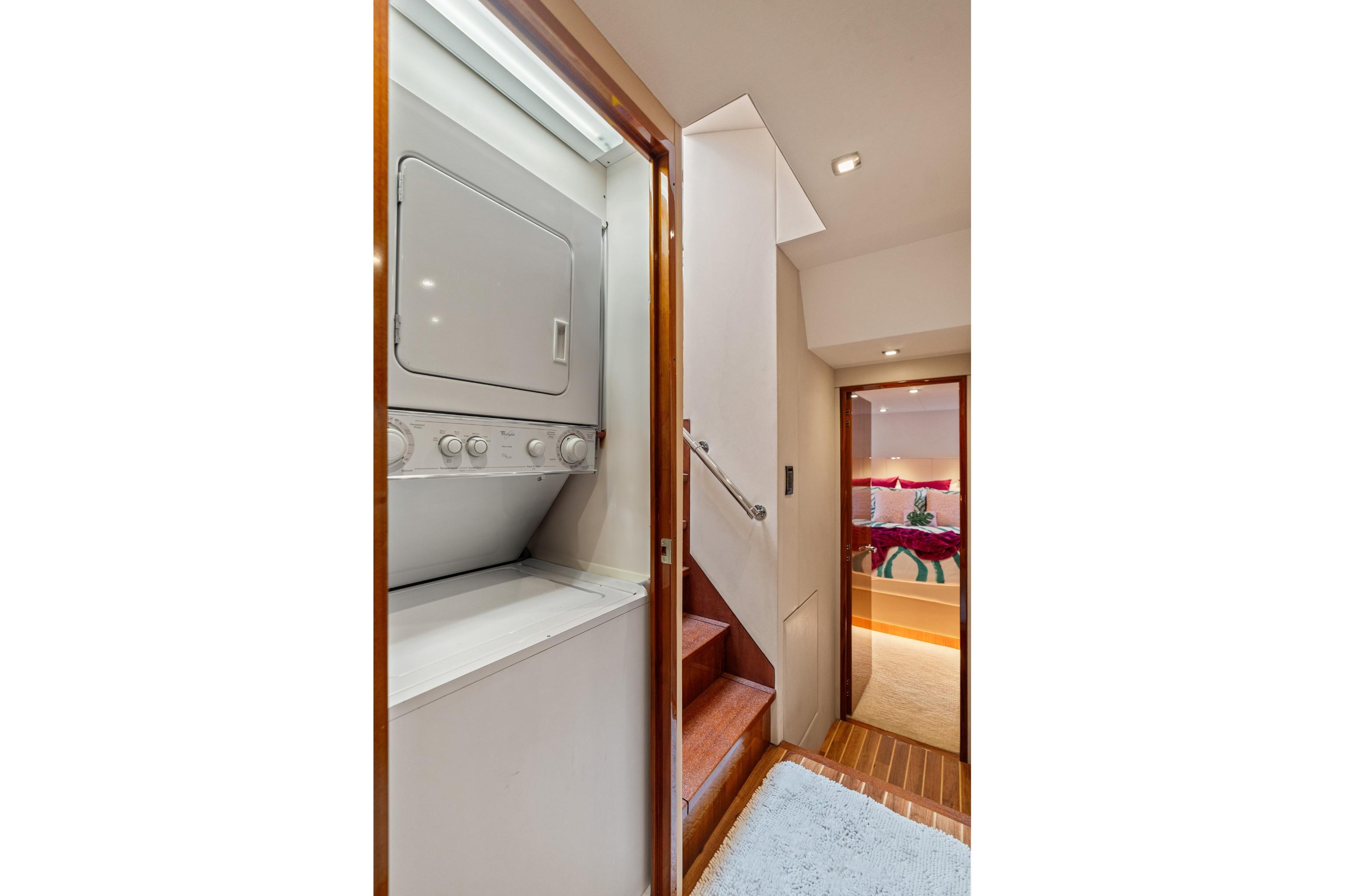 Laundry area and stairs inside 2008 Hatteras 64 Motor Yacht, leading to a cozy bedroom.