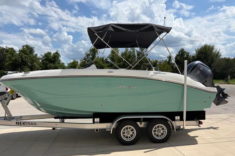 2026 Hurricane SunDeck Sport 2050 OB boat on trailer, under a cloudy sky.