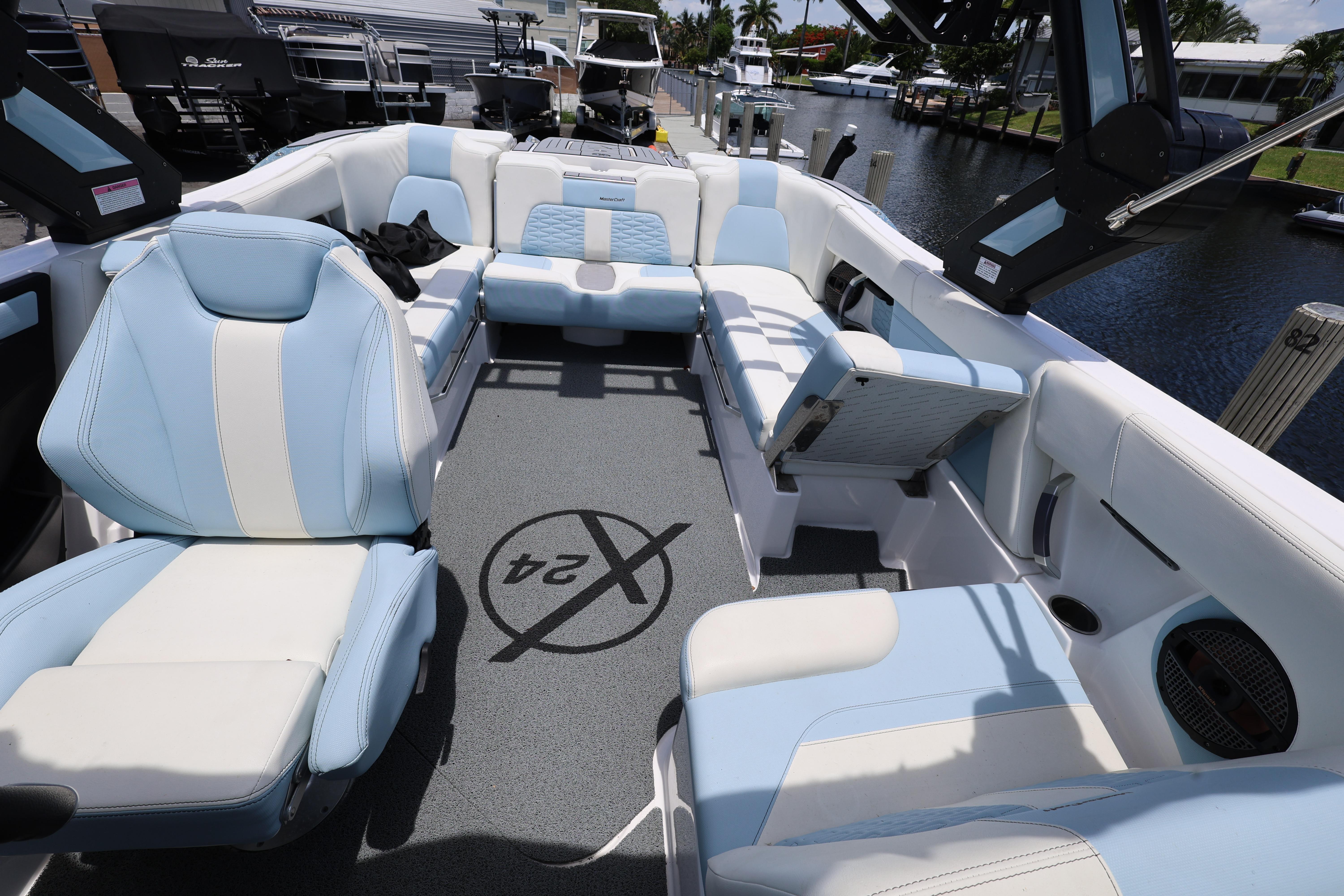 2023 MasterCraft X24 boat interior with blue and white seating, docked by a canal.