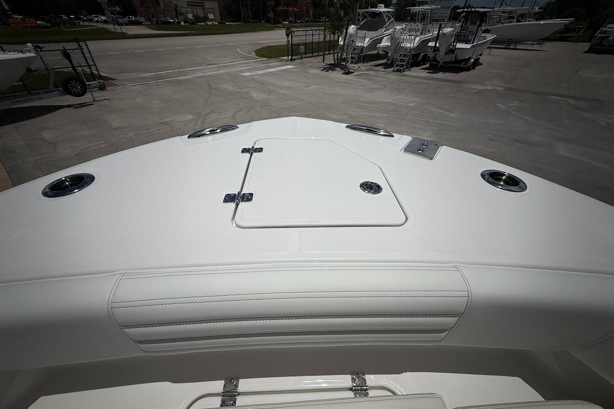 2026 Edgewater 250CC boat deck with storage hatch and cup holders, parked on concrete.