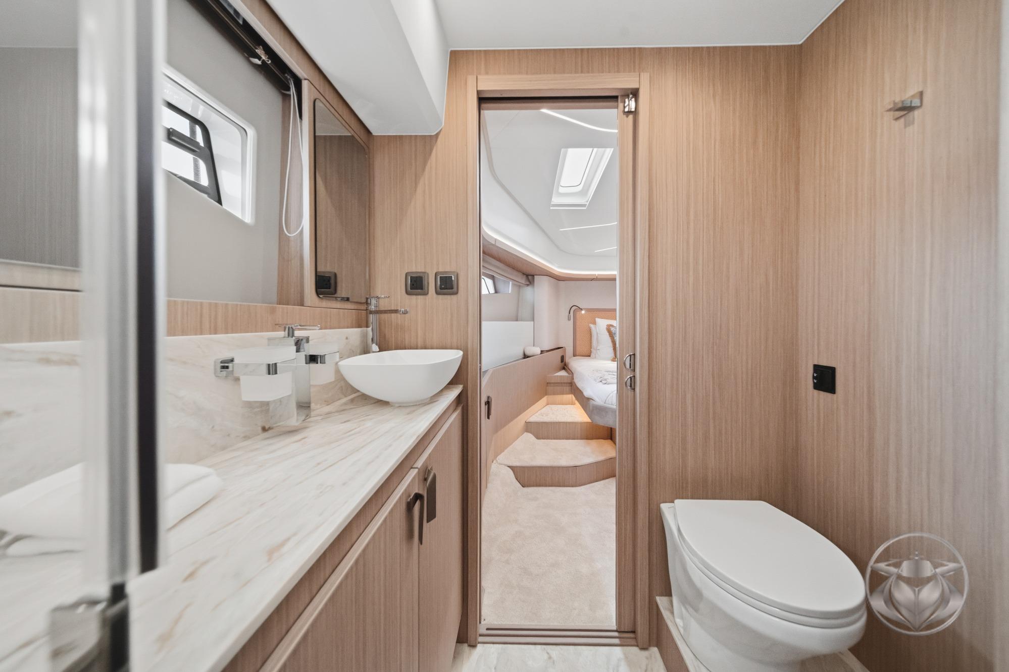 Modern yacht bathroom with wood accents, vessel sink, and view into bedroom. Prestige F4.9, 2026 model.