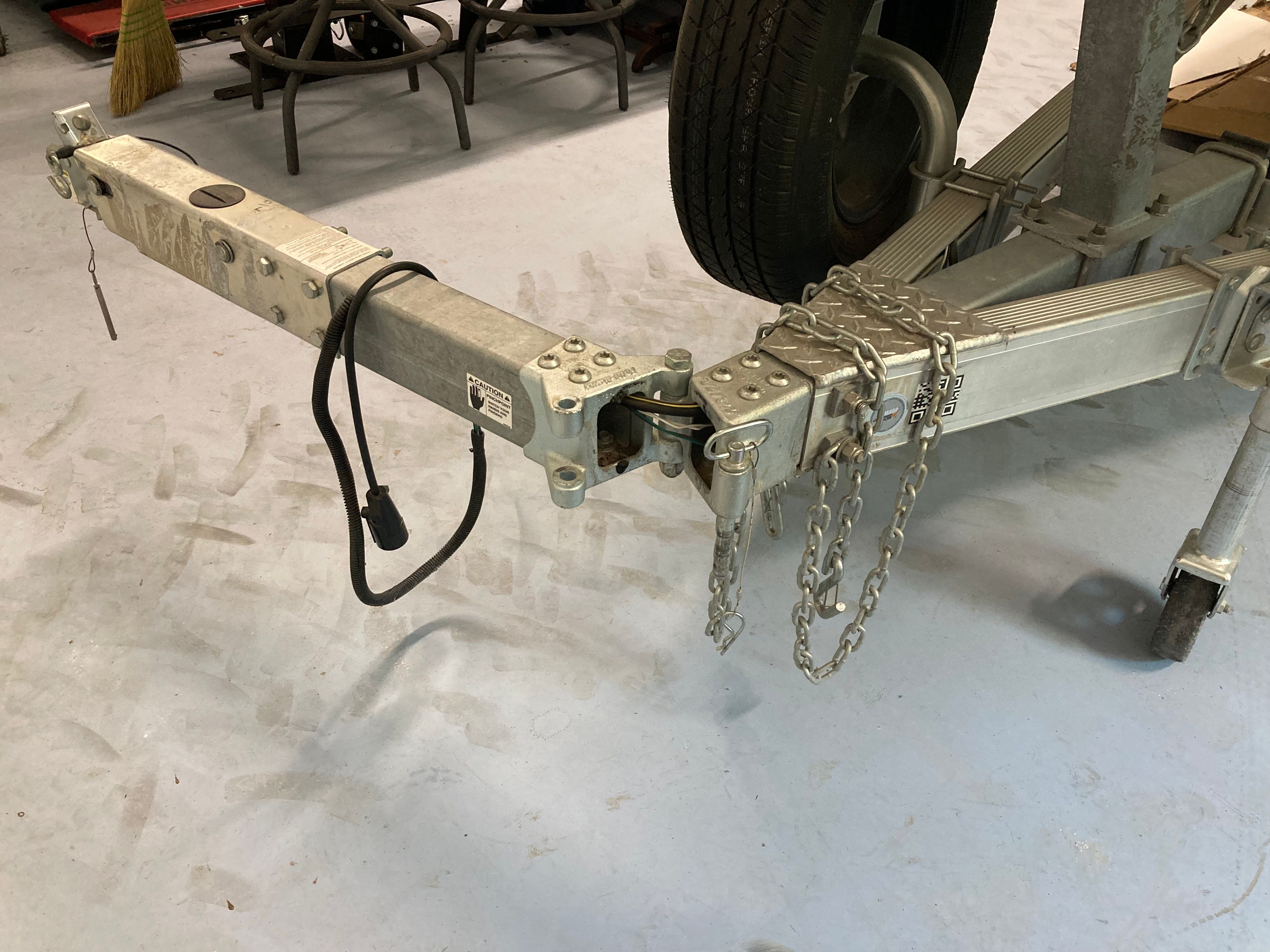 Trailer with safety chains and cables on a concrete floor.