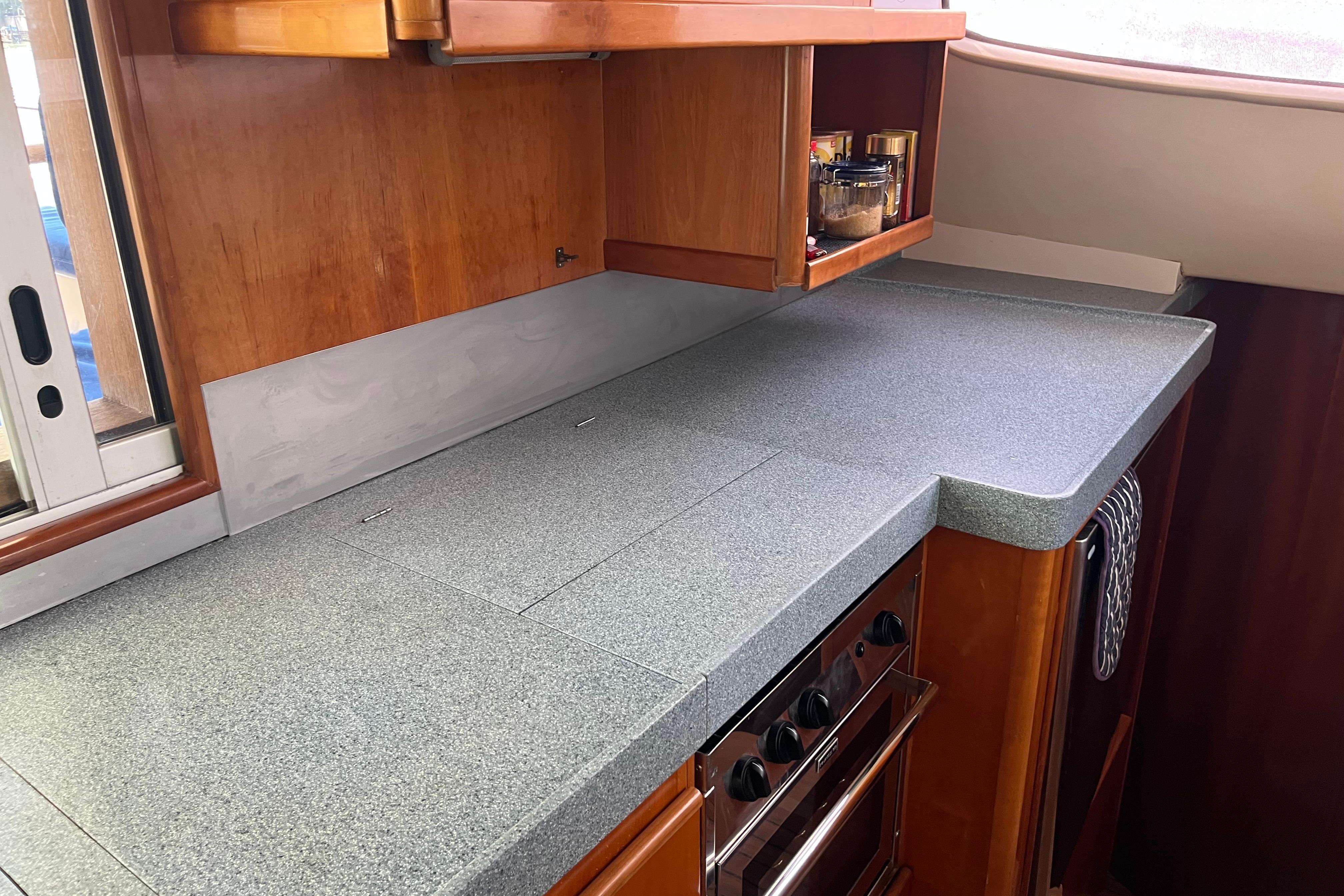Kitchen area of a 2004 Catana 471 Ocean Class yacht, featuring sleek countertops and wooden cabinetry.