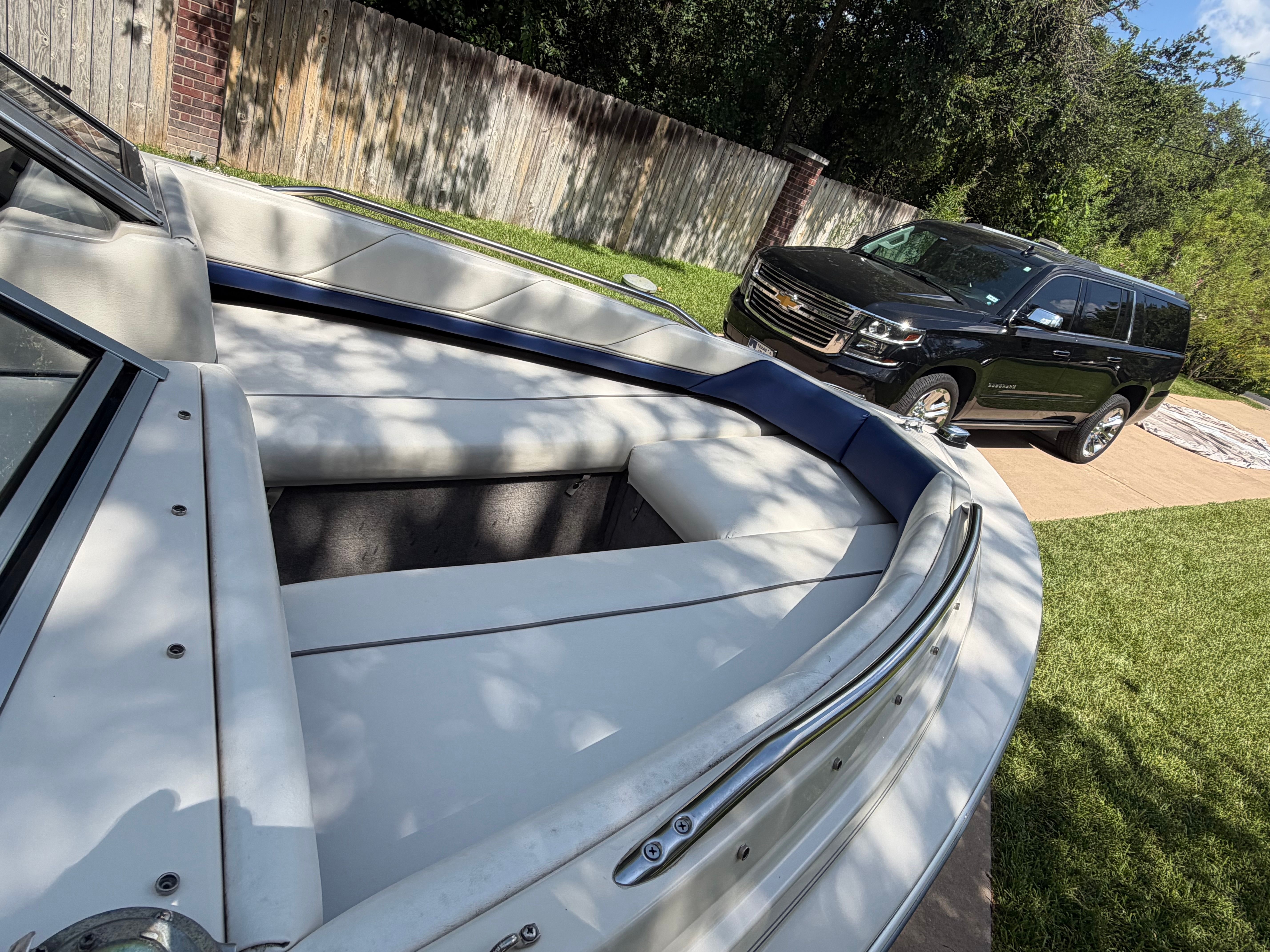 A 1994 Bayliner CAPRI is parked on grass next to a black SUV.