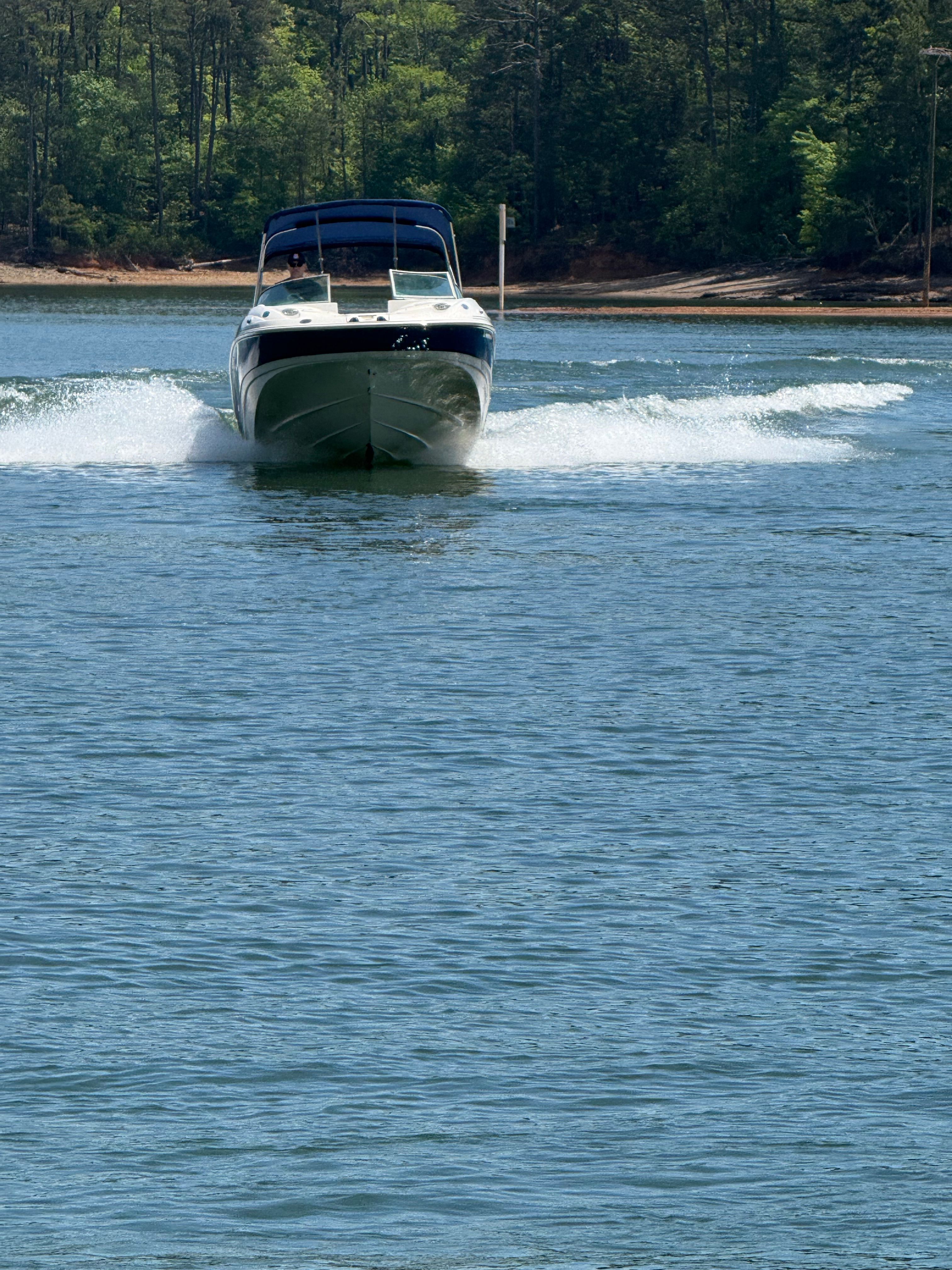 A 2005 Monterey 223 Explorer Sport cruising on a lake, surrounded by trees.
