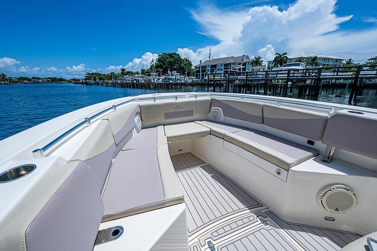 2019 Cobia 320 Center Console boat with spacious seating, docked by a scenic waterfront.