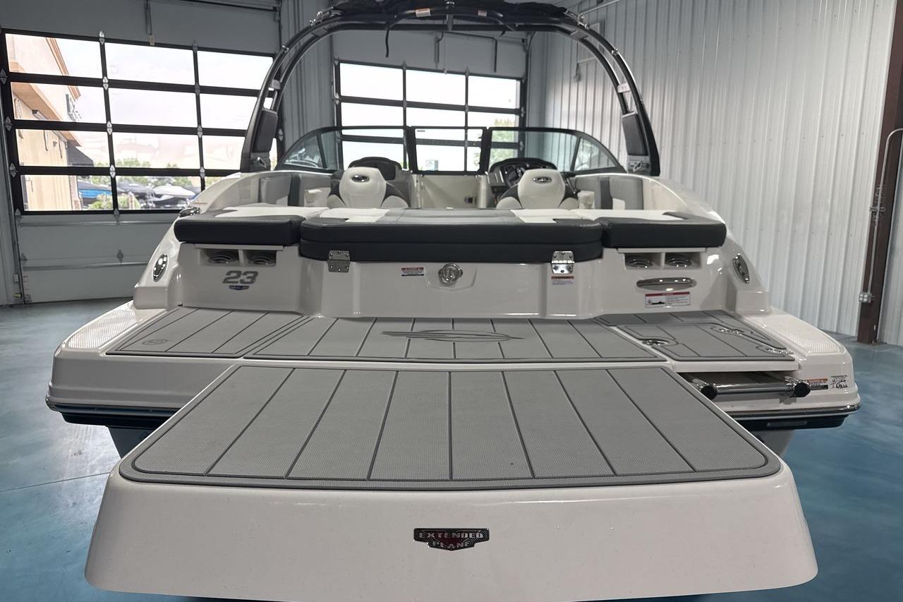 The image shows the stern of a Chaparral 23 SSi boat in a warehouse.