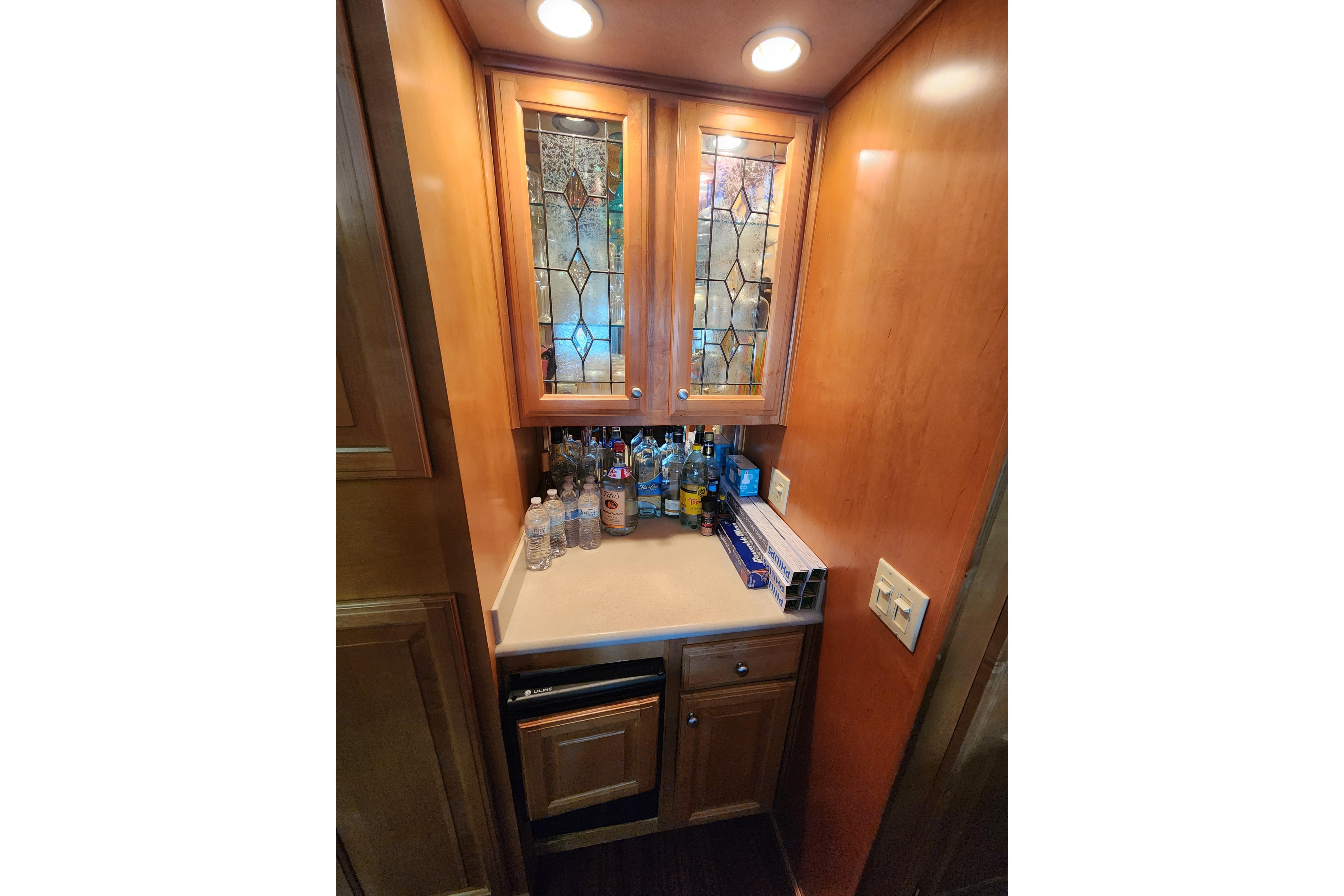 Wooden cabinet with glass doors, countertop with bottles, in a 2000 Sharpe model 85.