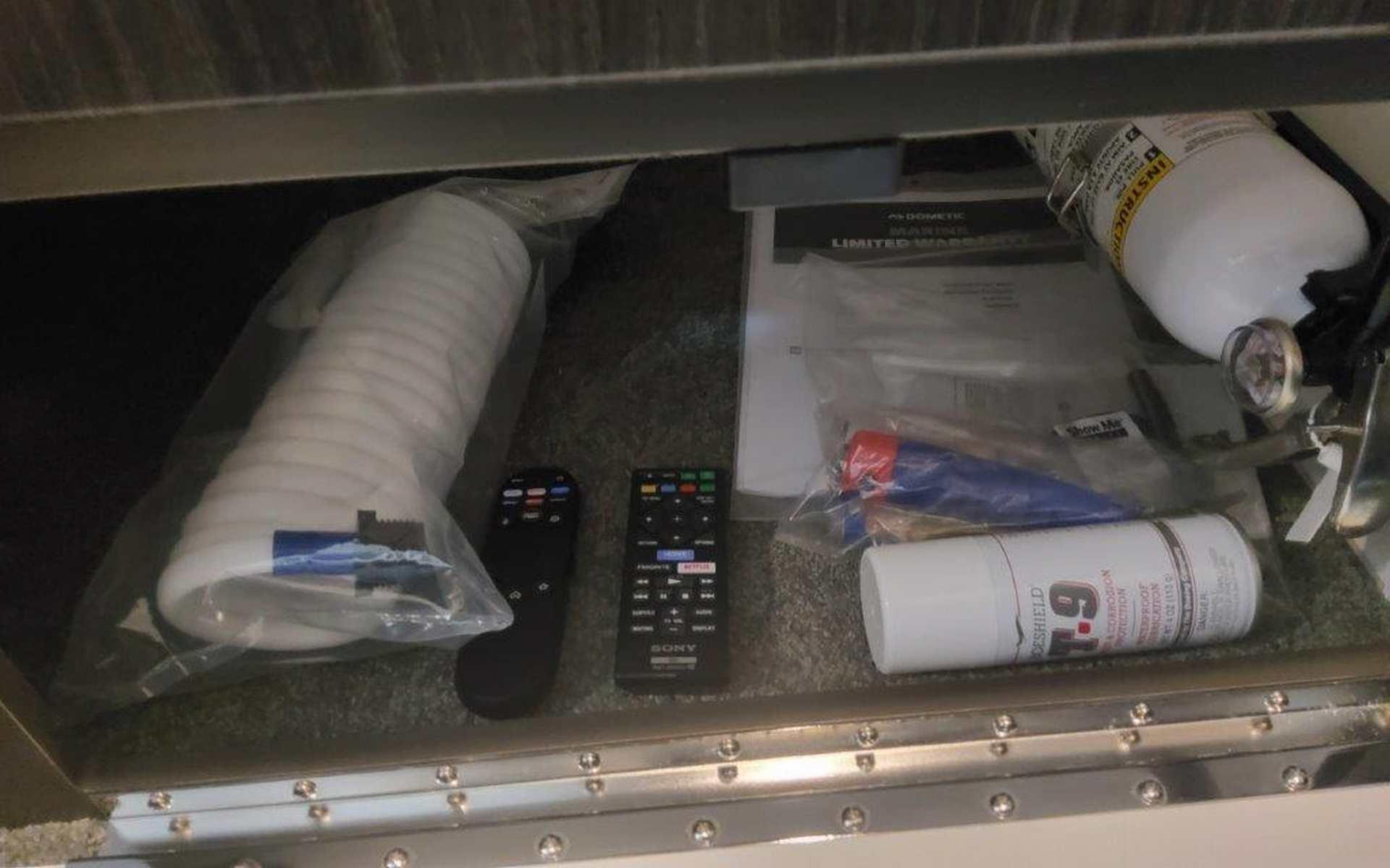 Storage compartment in 2025 Formula 330 Crossover Bowrider I/O with remotes, documents, and safety equipment.