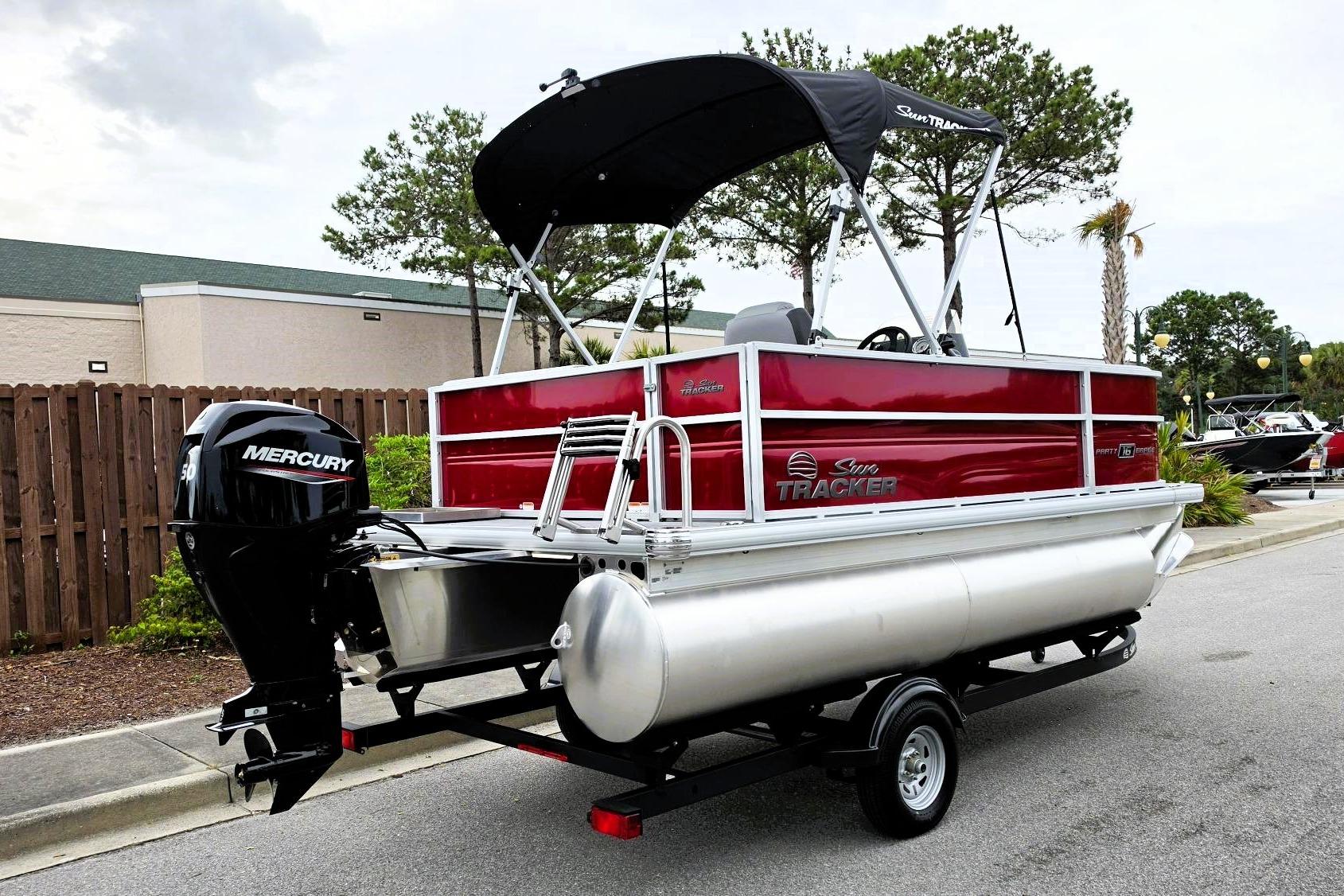 2026 Sun Tracker Party Barge 16 DLX pontoon boat with Mercury engine, parked outdoors.
