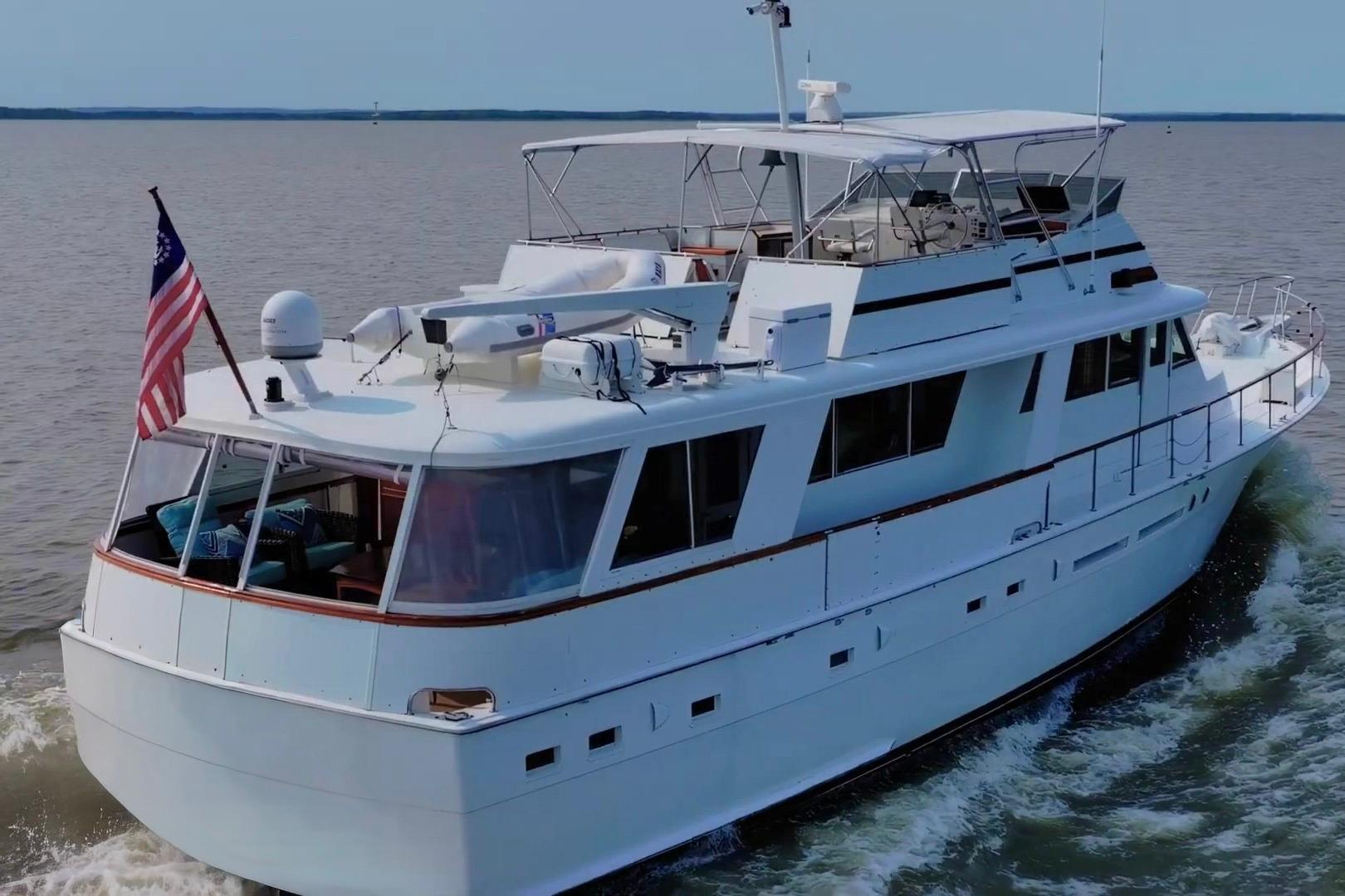 1980 Hatteras 70 Motor Yacht cruising on open water with American flag.