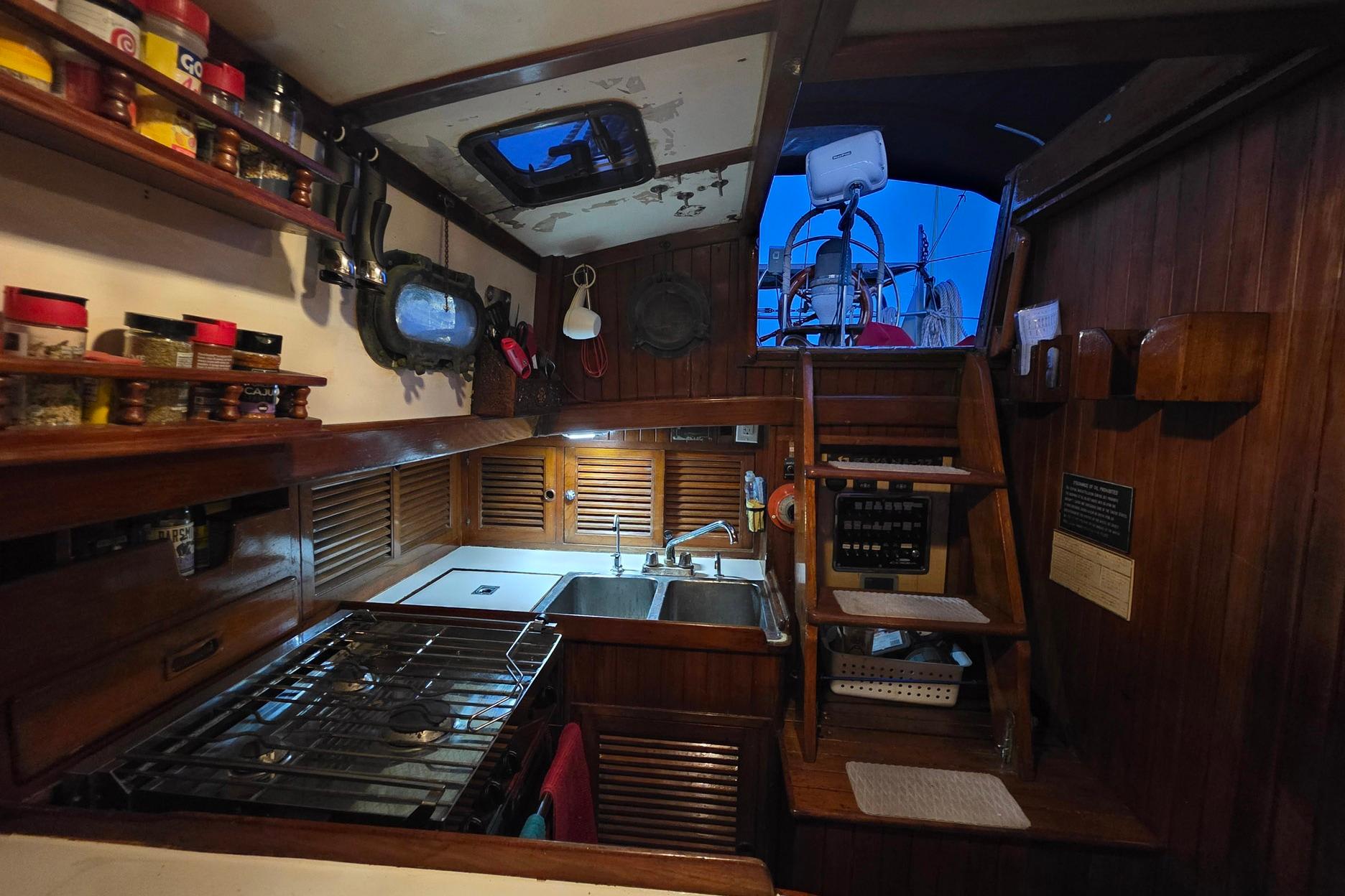Cozy 1982 Tayana 37 yacht galley with wooden cabinetry and nautical decor.