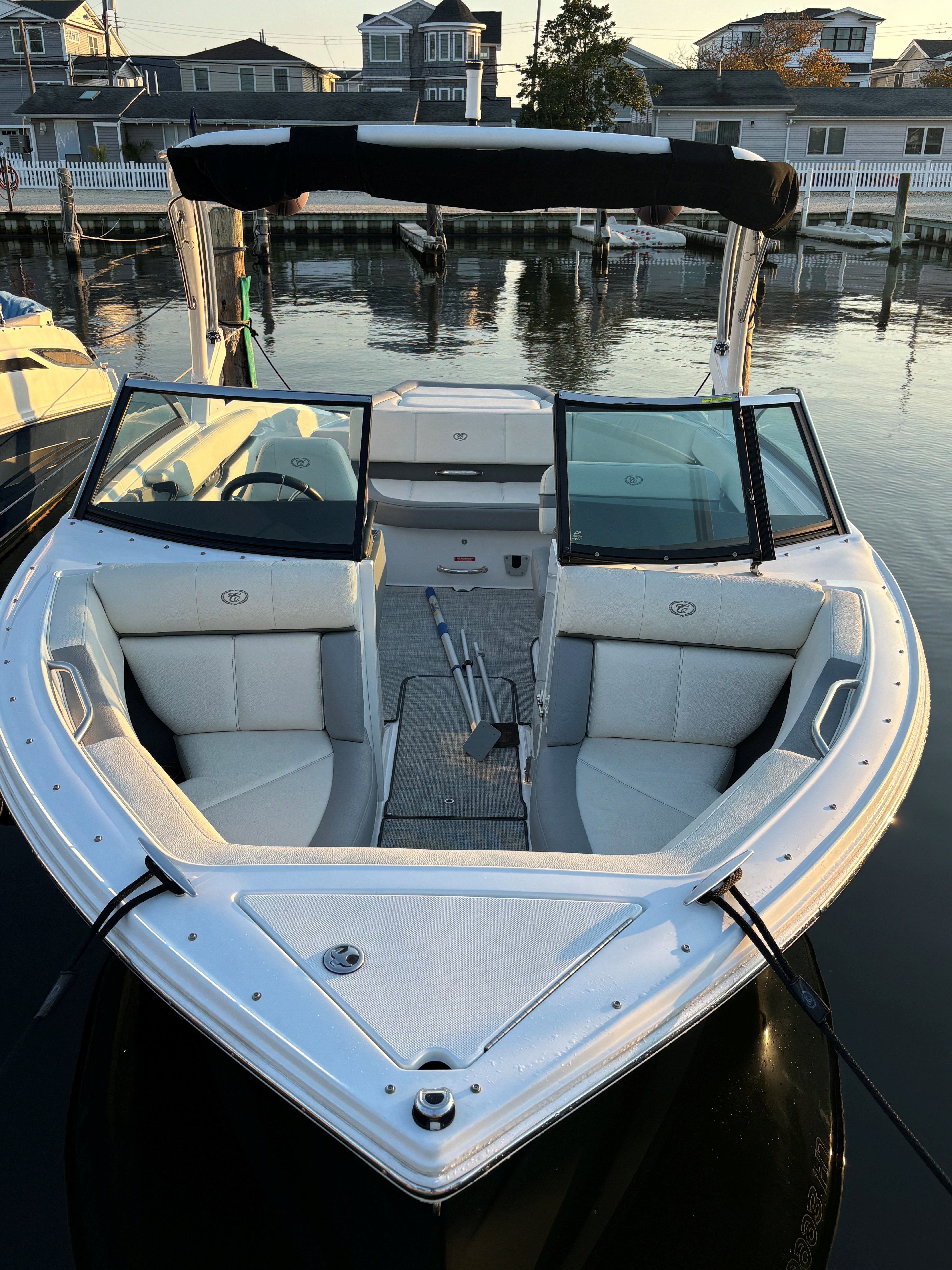 A 2019 Cobalt CS22 boat docked in calm waters. It features white upholstery and a black canopy.