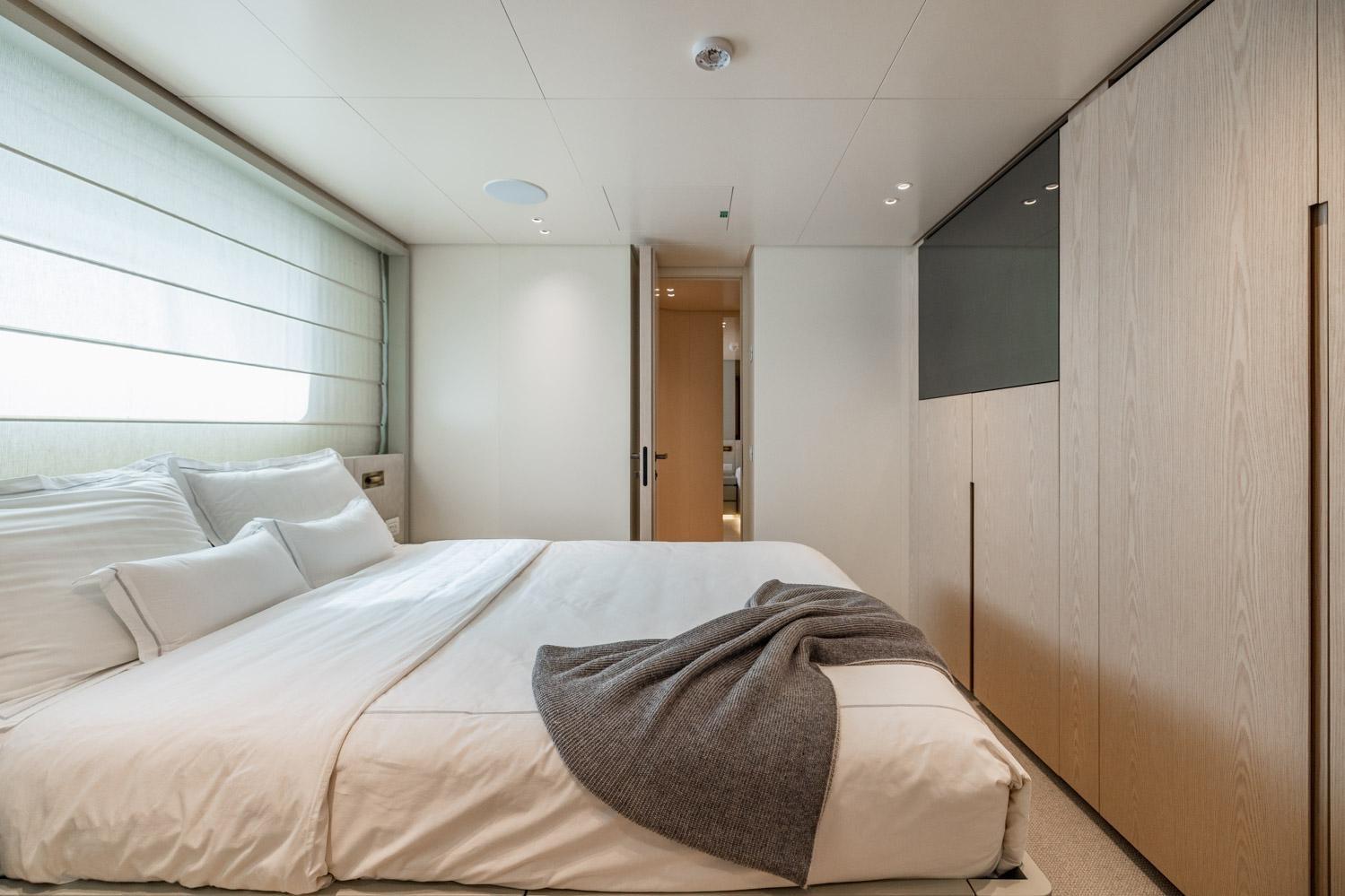 Luxurious bedroom interior on 2022 Sanlorenzo SD96 yacht, featuring modern design and cozy bedding.