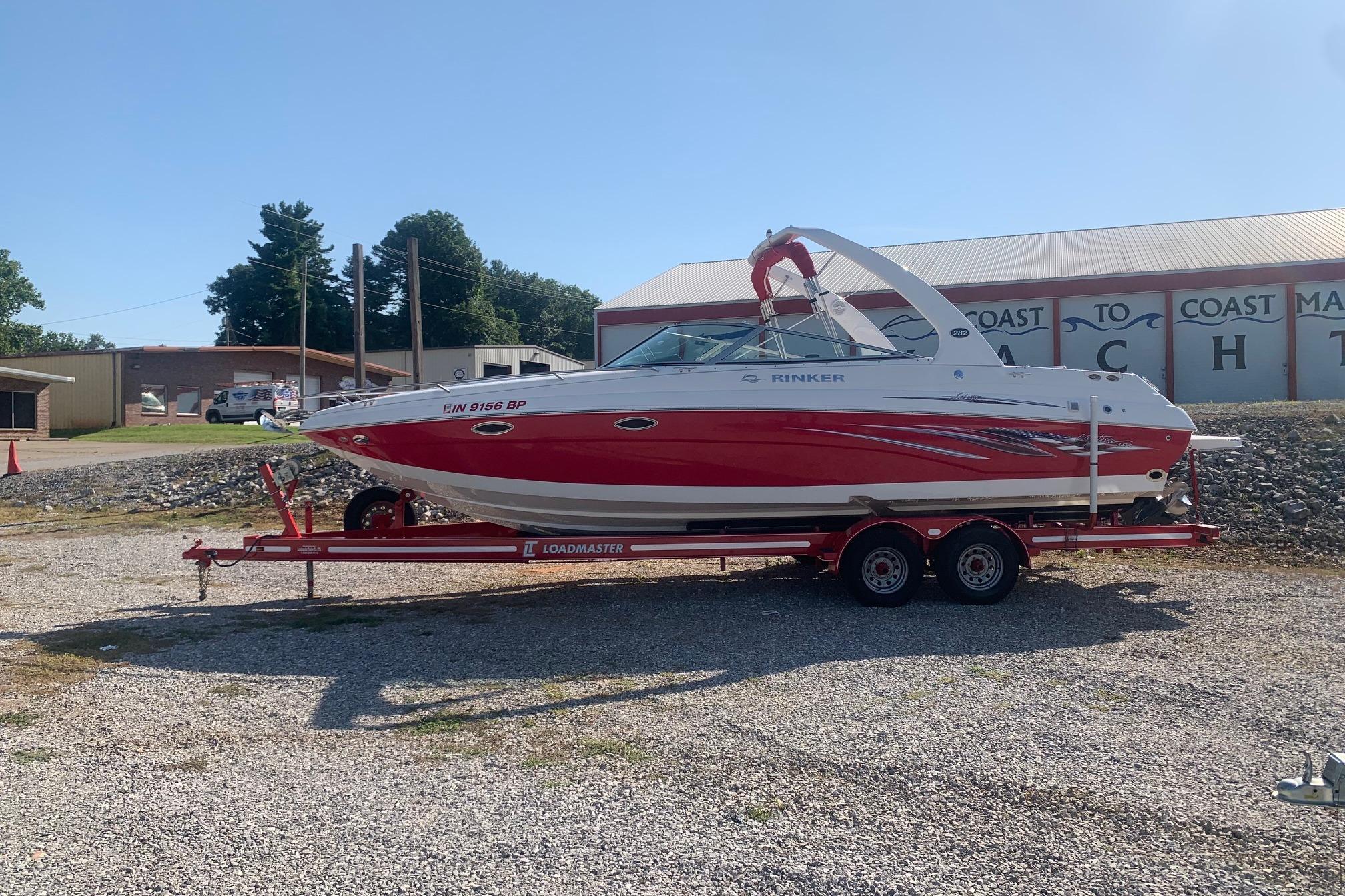 2006 Rinker 282 Captiva Cuddy boat on trailer, red and white design, parked outdoors.
