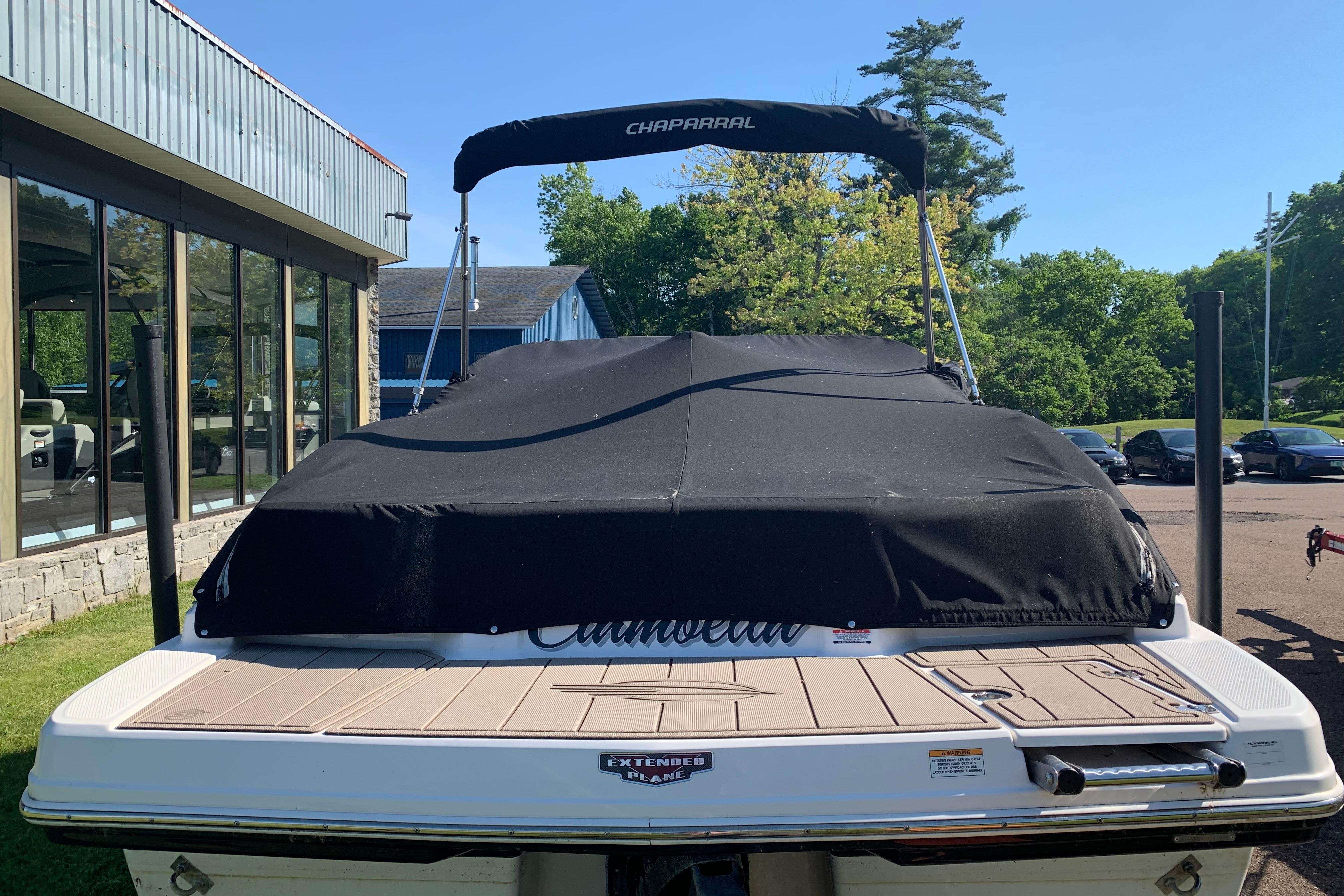 2022 Chaparral 23 SSi boat with black cover, parked outdoors near showroom.
