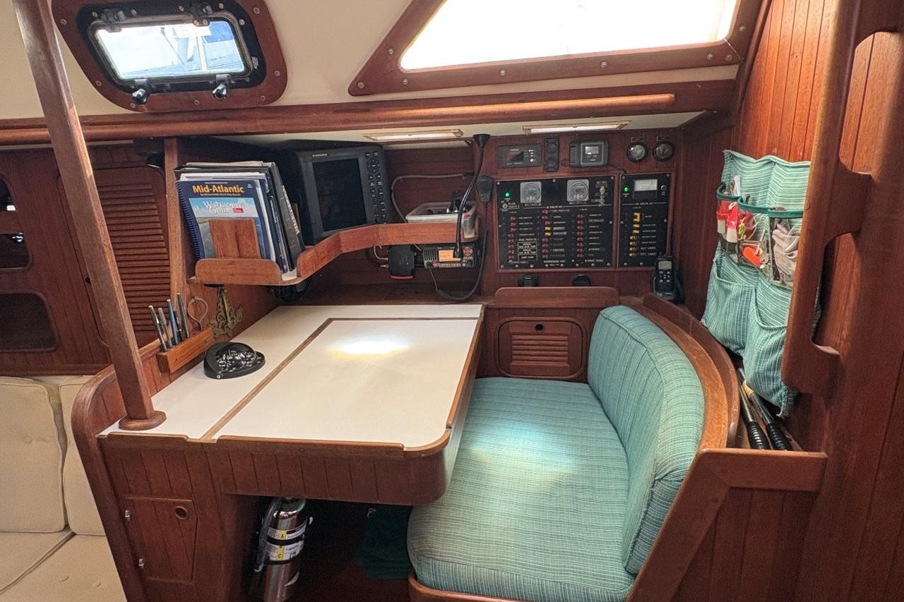Cozy navigation station in 1981 Norseman 447 sailboat with wood paneling and teal seating.