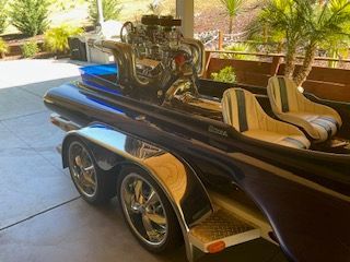 A 1980 Sanger HYDRO V DRIVE boat with a prominent engine and striped seats on a trailer.
