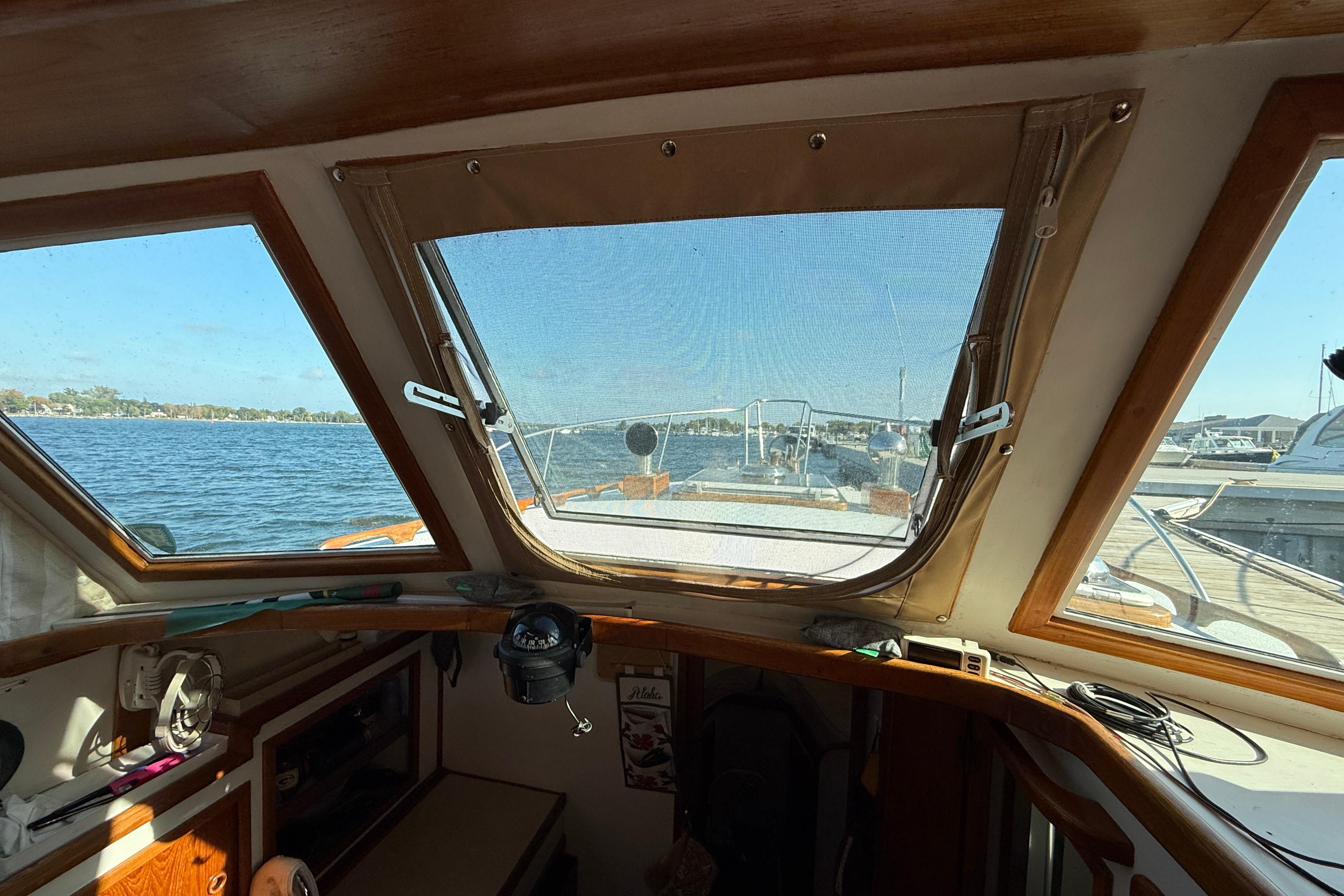 Interior view from 1983 Wilbur 34 Fly Bridge Cruiser, overlooking serene waters and marina.
