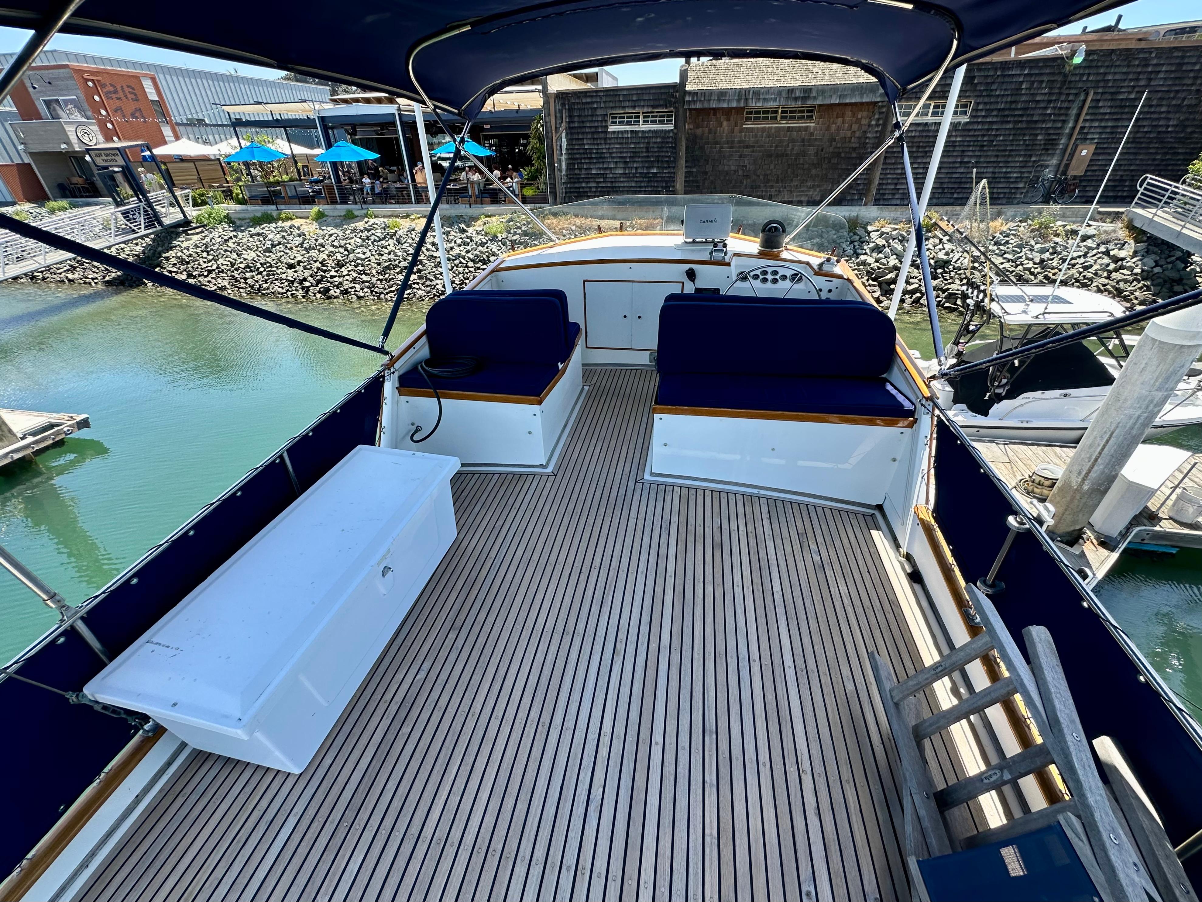 1977 Grand Banks 42 Classic yacht deck with seating and canopy at marina.