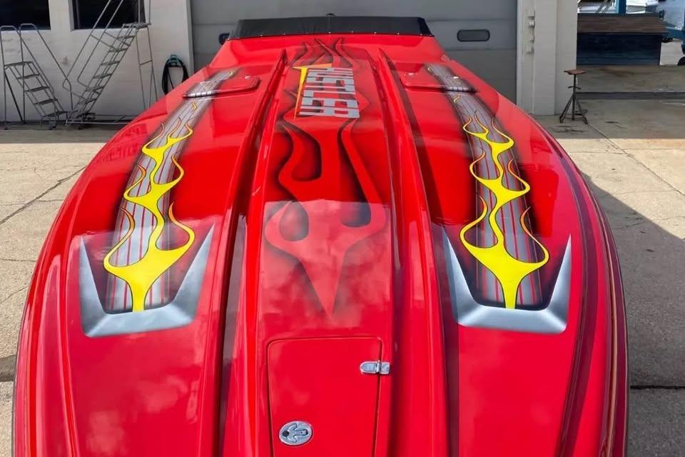 Red 2005 Hustler 388 SLINGSHOT boat with flame graphics on deck.