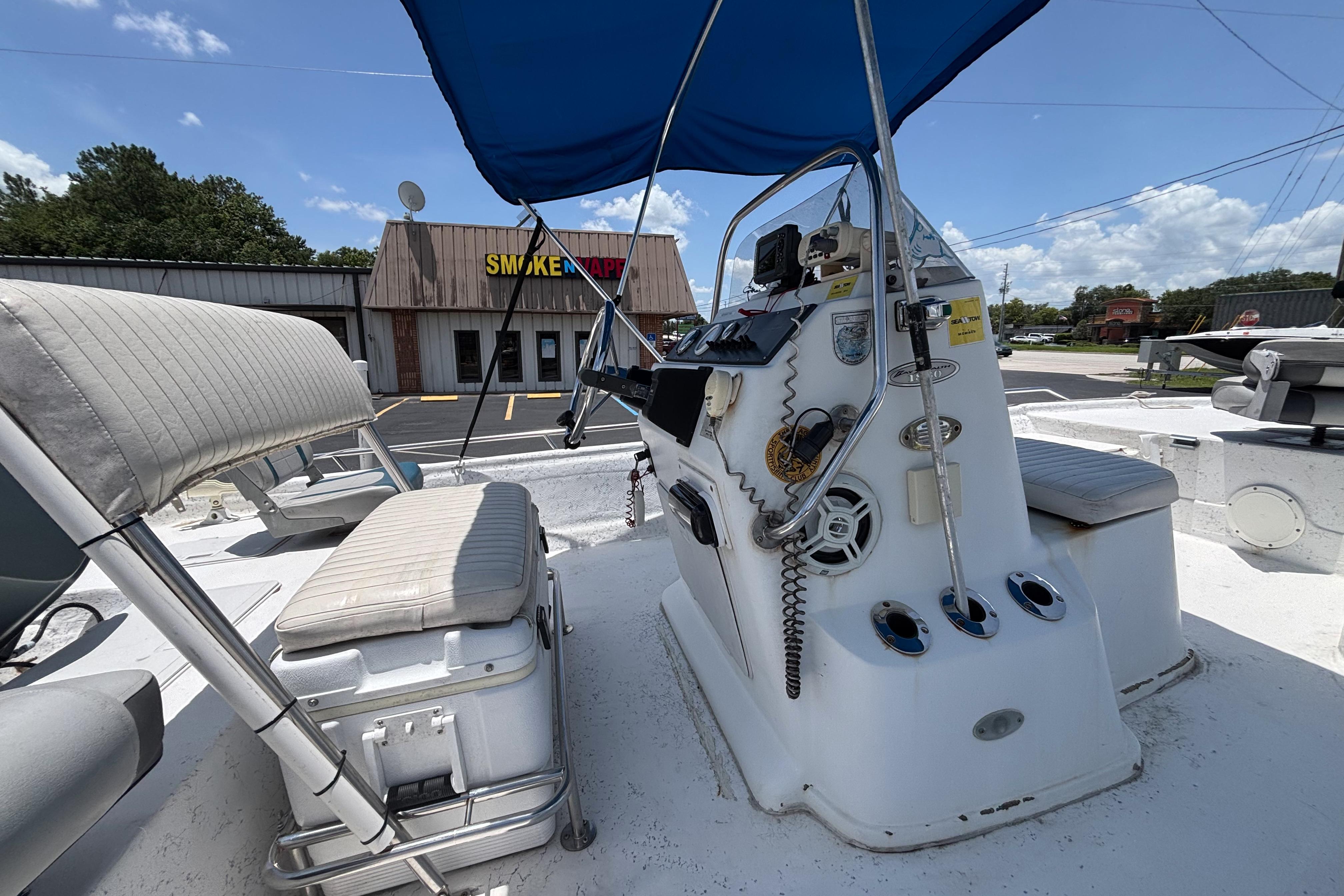 2000 VIP 1880 BAY STEALTH boat interior with blue canopy and seating, parked near a store.