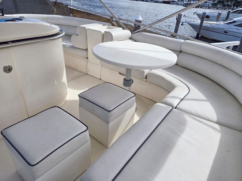 1998 Viking Princess 56 Sport Cruiser, white seating area with round table, docked by water.