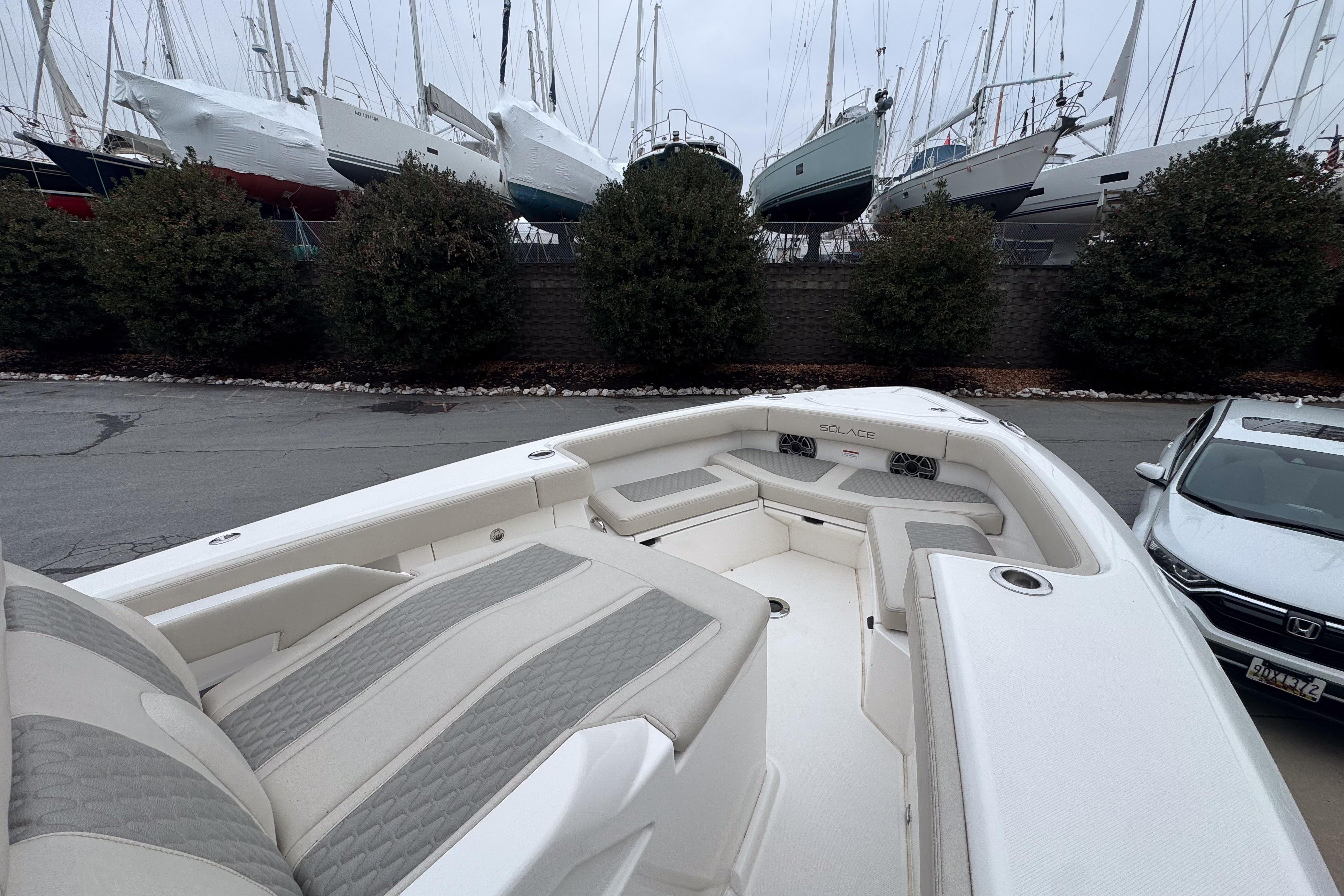 2025 Solace 30 HCS boat interior with cushioned seating, docked near parked cars.
