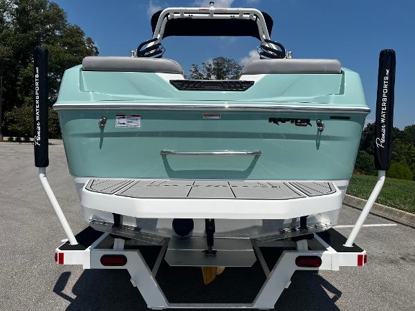 2025 Moomba Max boat on trailer, rear view, mint green color, parked outdoors.