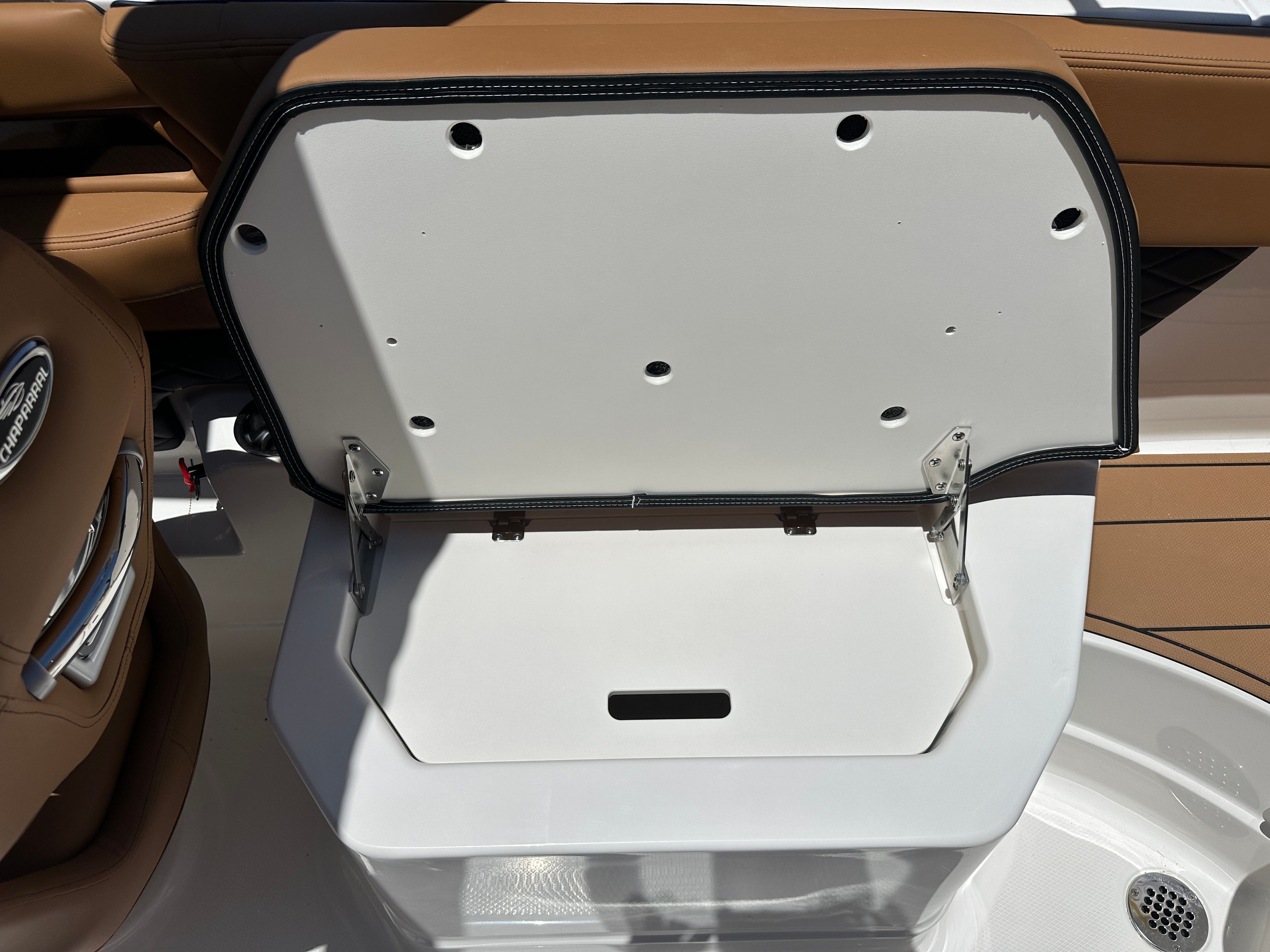 An open storage compartment on a Chaparral 26 Surf boat, surrounded by brown seating.