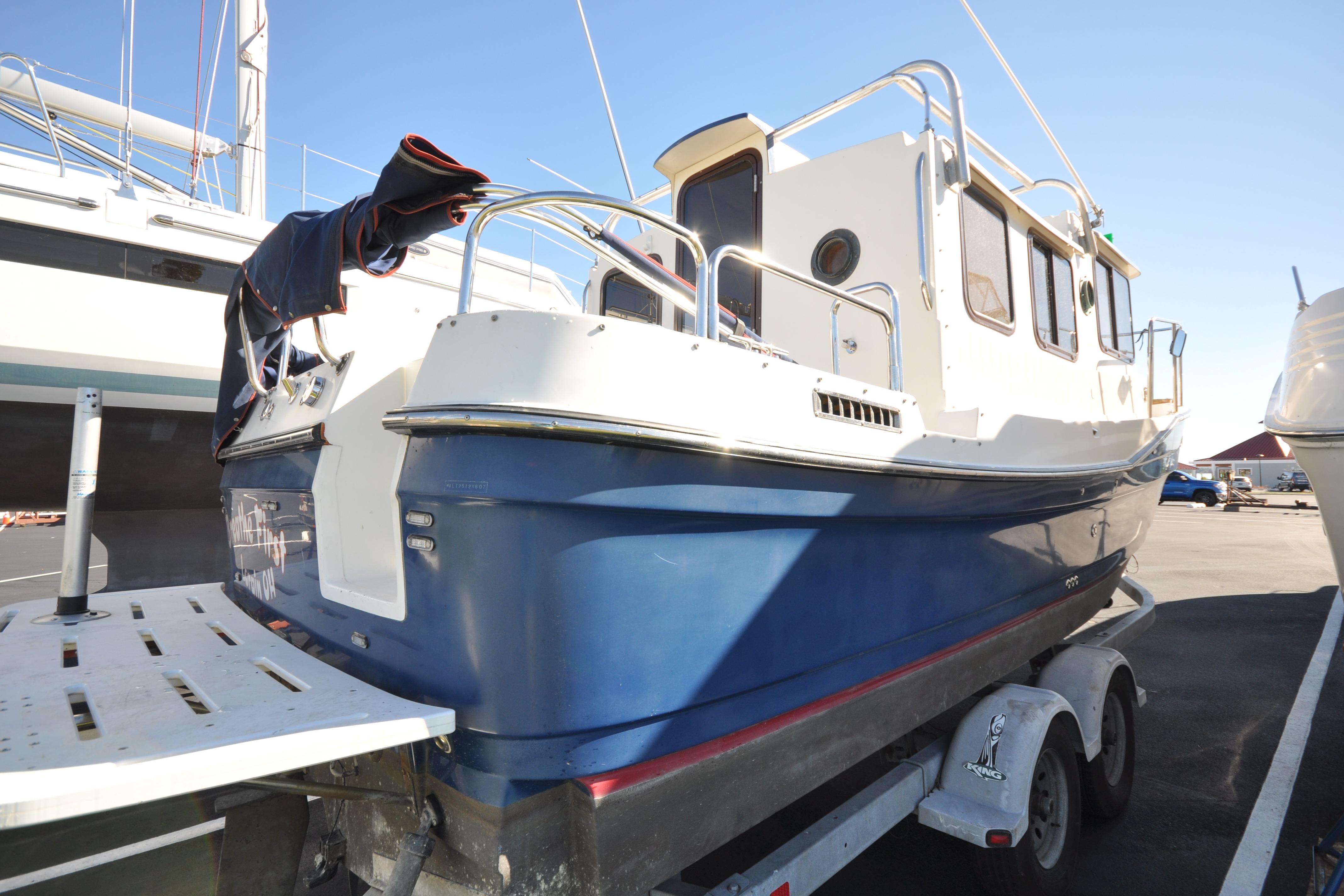 2007 Ranger Tug R-25 boat on trailer, blue hull, docked in marina.