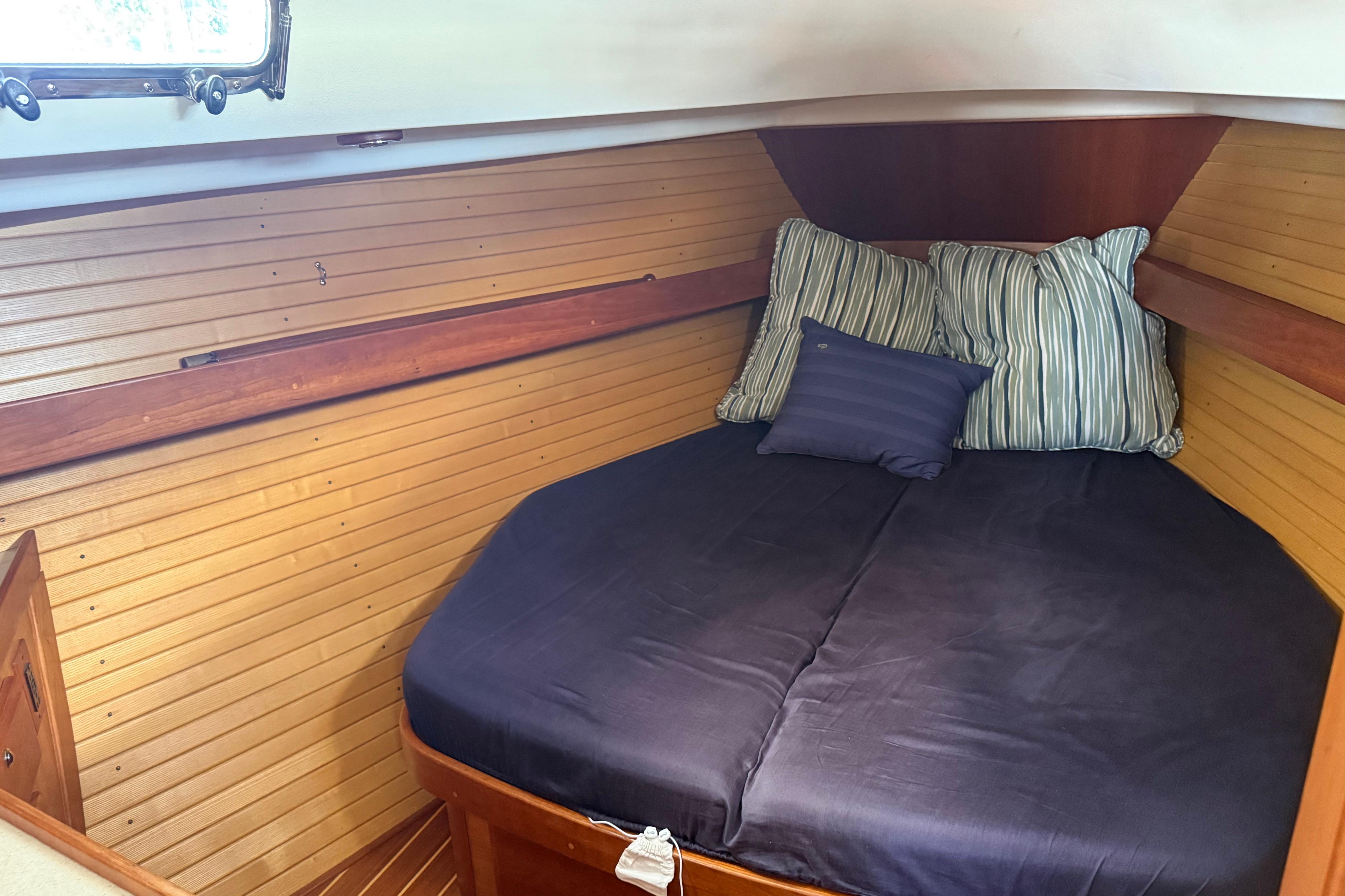 Cozy cabin interior of 2004 Sabre 386 sailboat with striped pillows and wooden paneling.