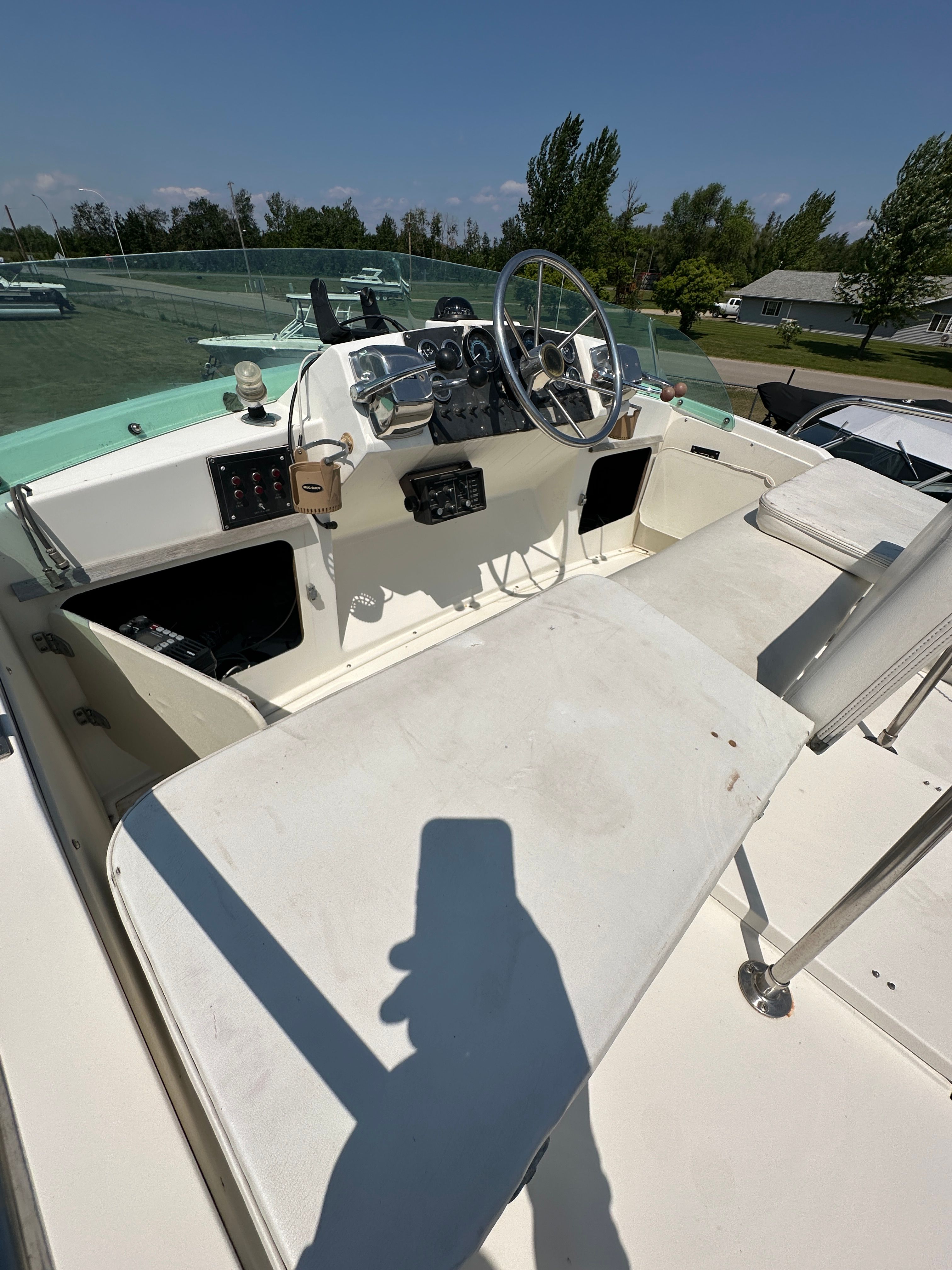 The image shows the helm of a 1983 Bertram Flybridge Cruiser with a white console and large steering wheel.