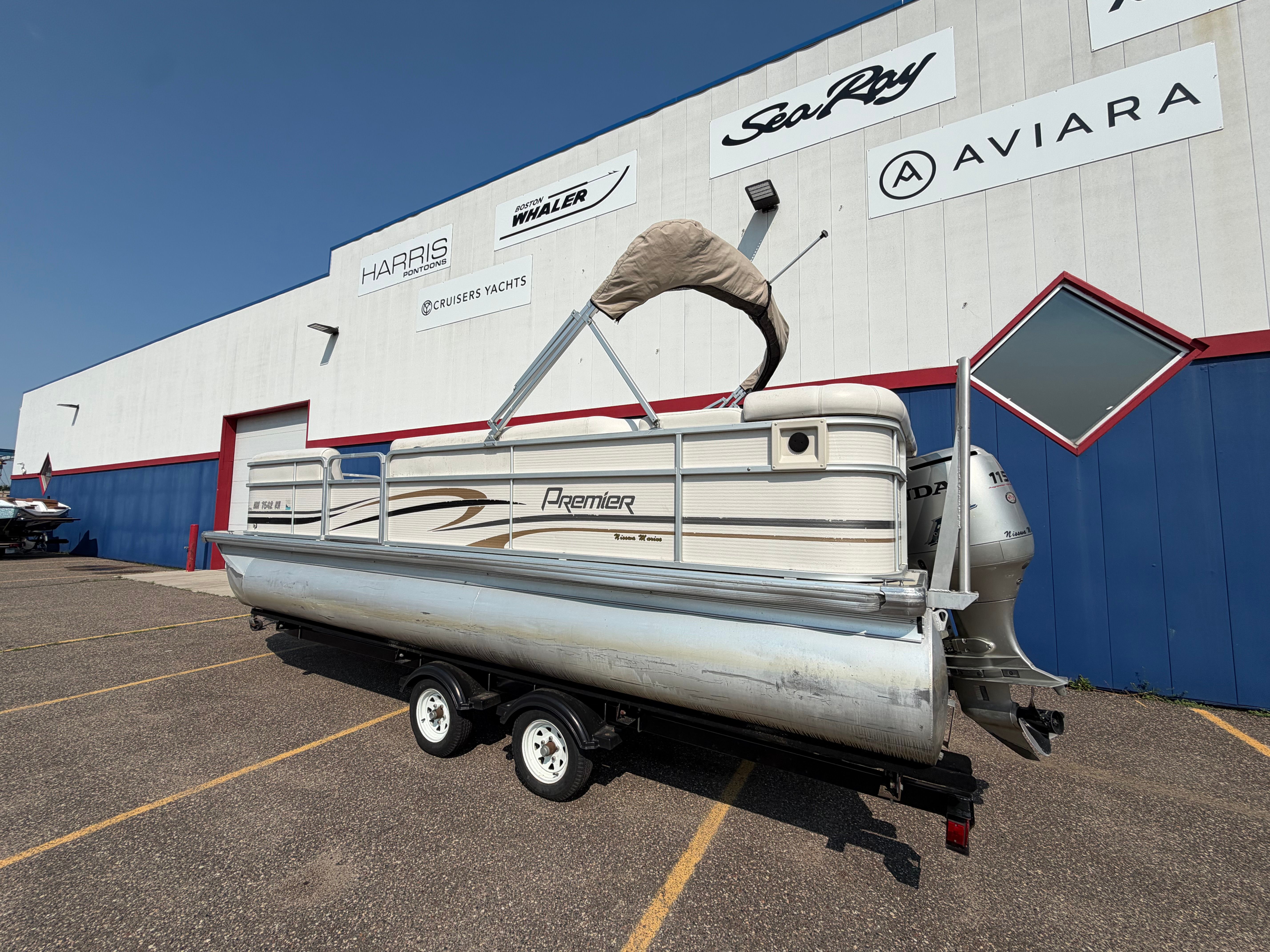 A 2007 Premier 225 Sunsation pontoon boat on a trailer in front of a building.