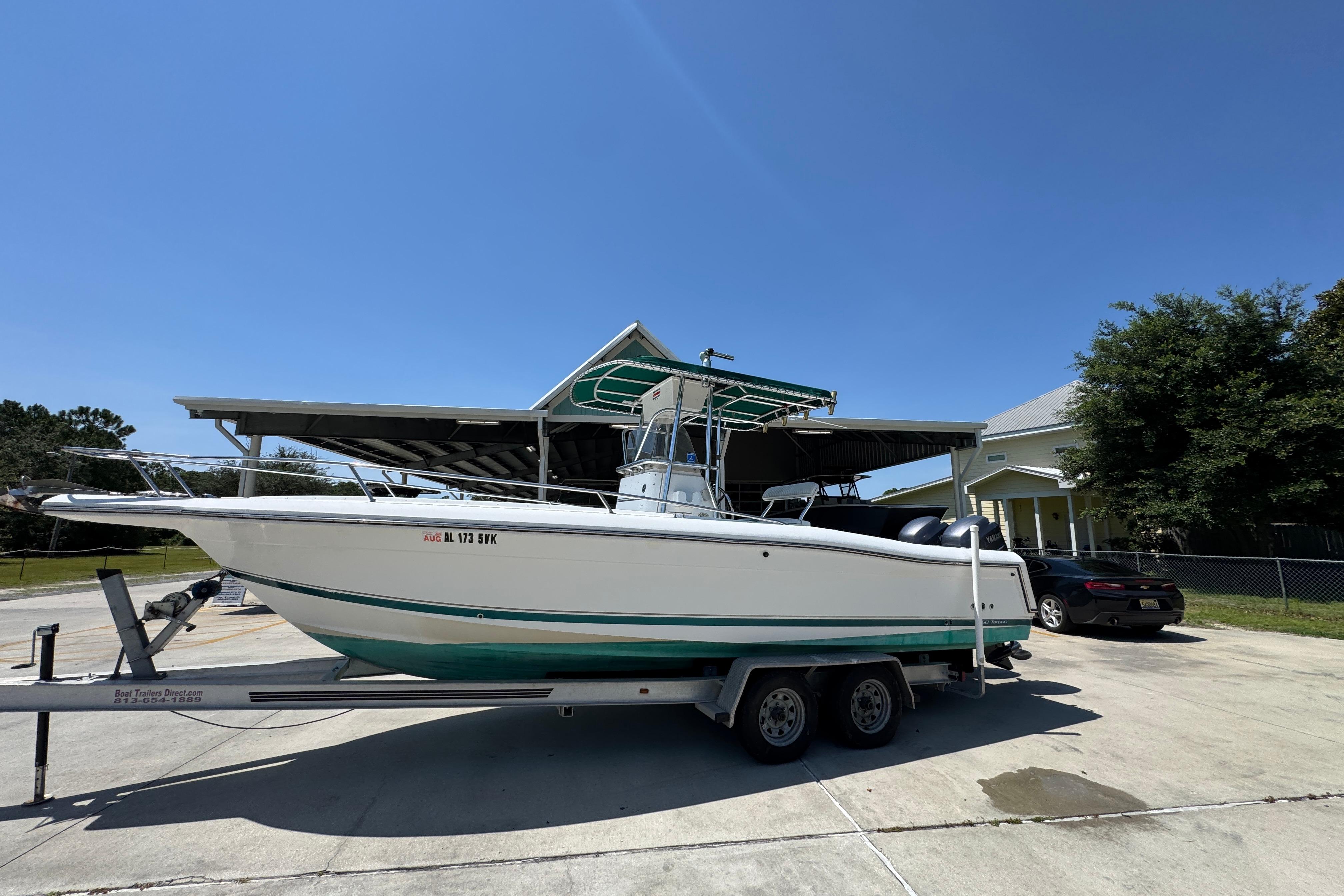 2000 Stamas 250 Tarpon boat on trailer, parked outdoors under clear blue sky.