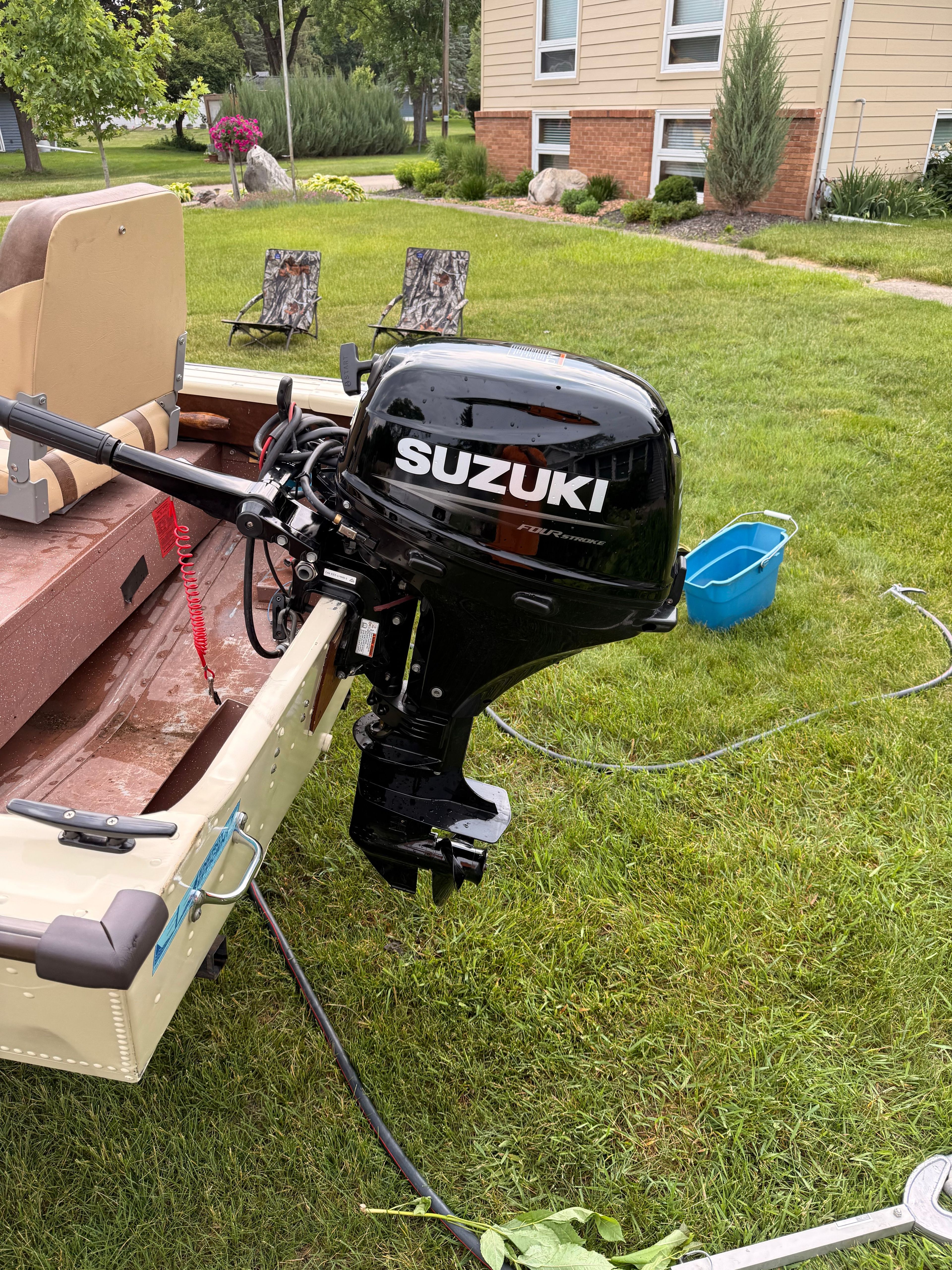 A 1985 Grumman boat with a Suzuki outboard motor on a lawn.