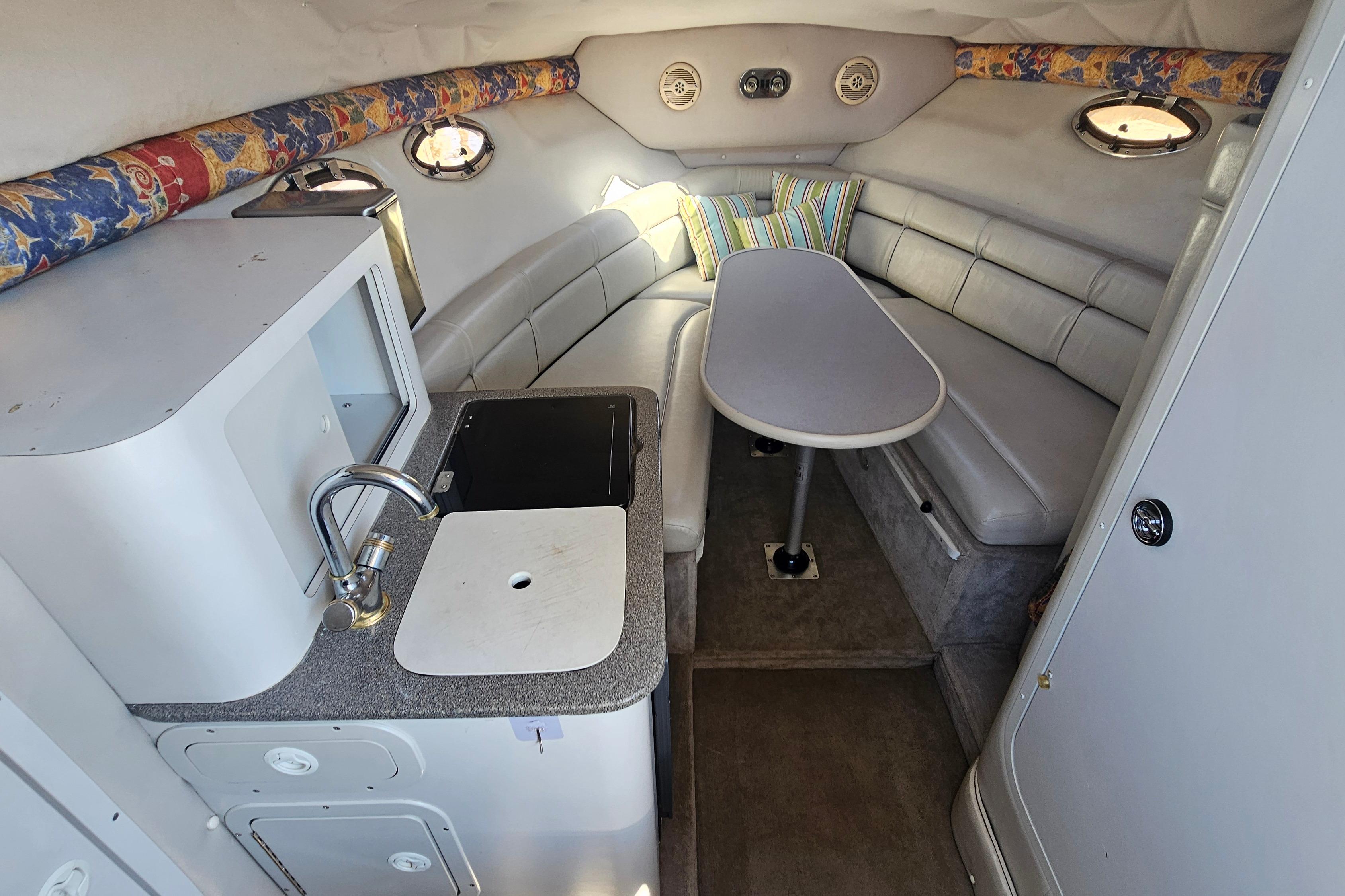 Interior of a 2000 Crownline 242 CR boat with kitchenette and seating area.