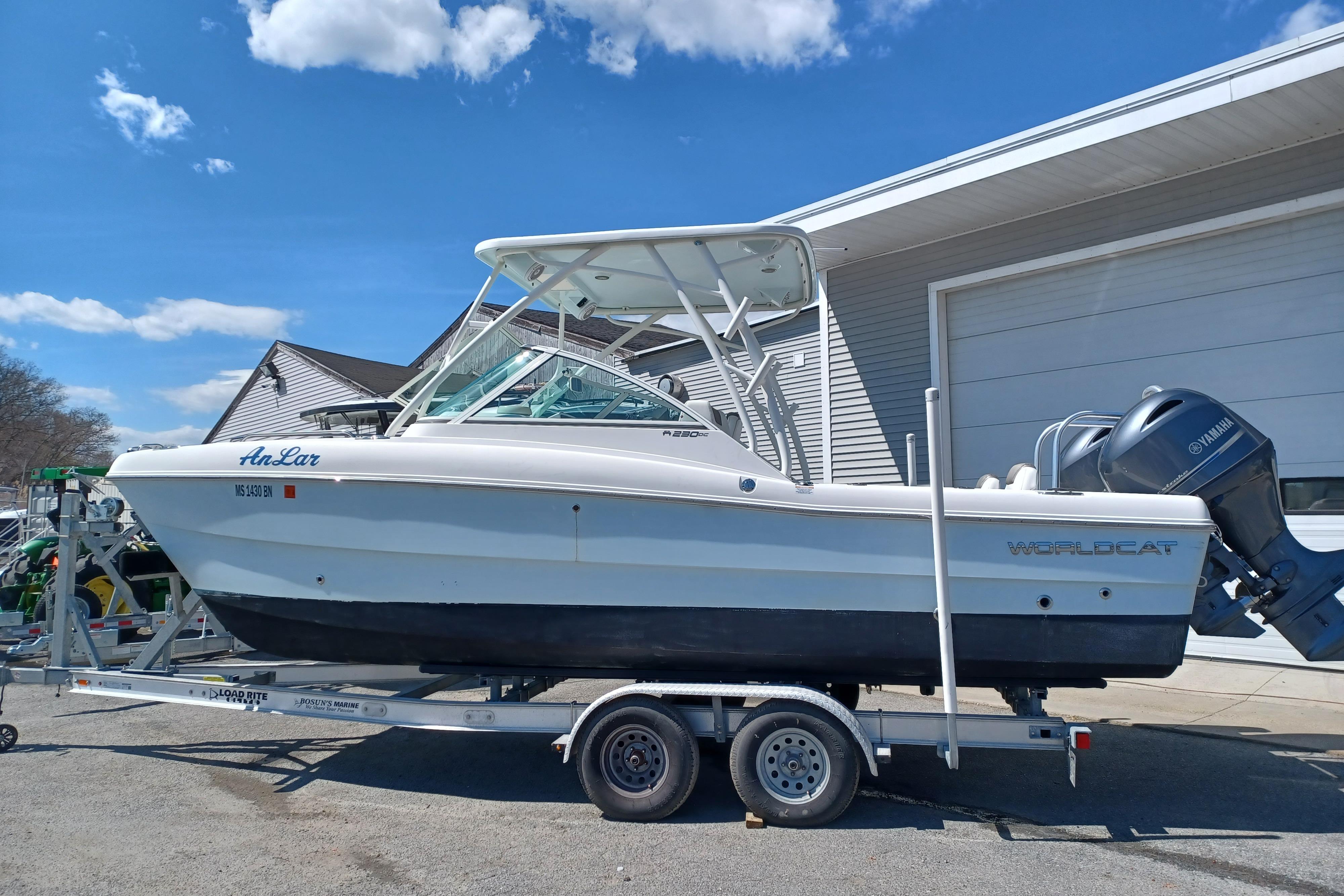 2020 World Cat 230 DC boat on trailer, parked outside a garage under a clear blue sky.