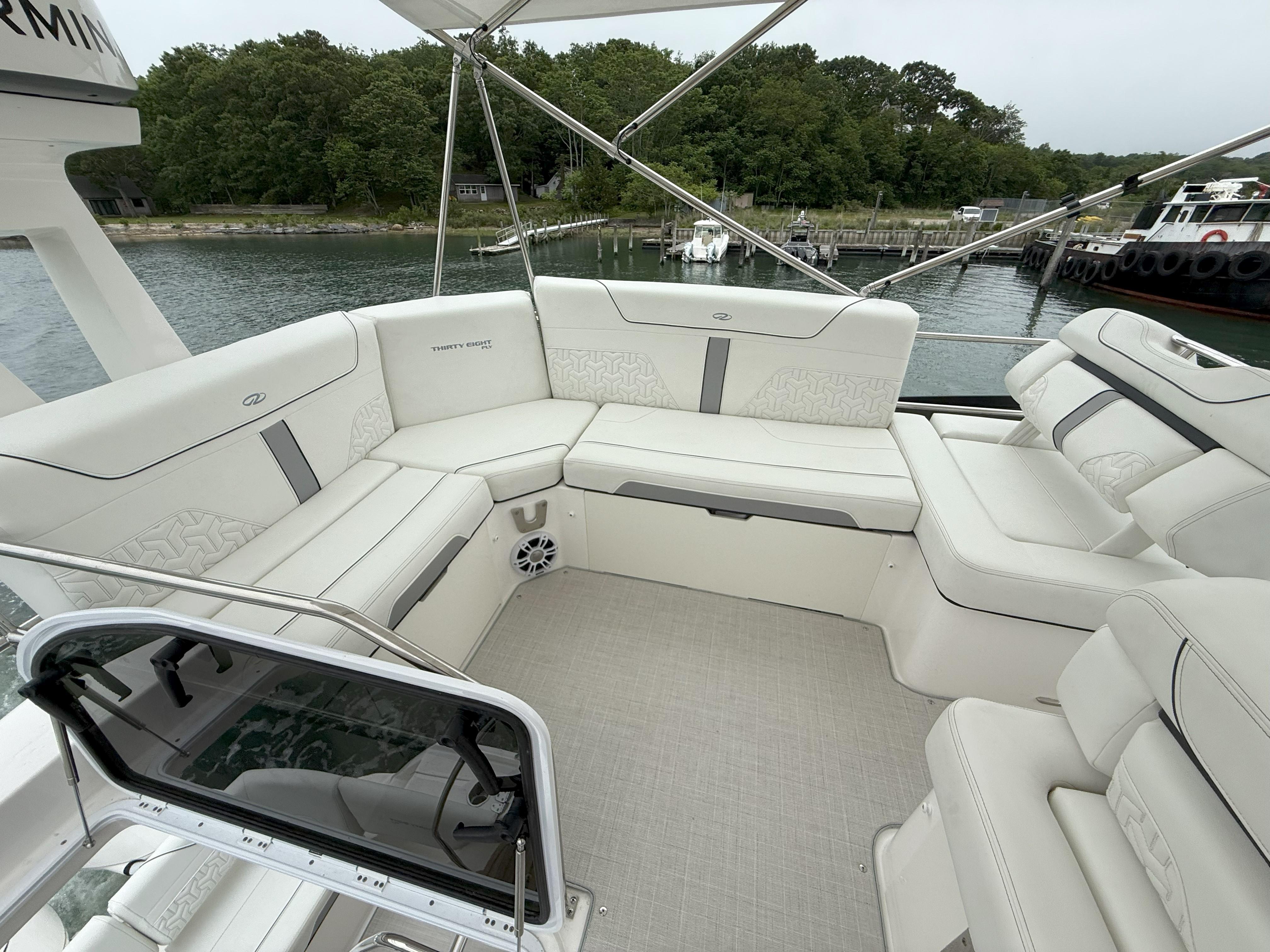 Luxurious seating area on a 2025 Regal 38 FXO yacht, docked by a serene waterfront.