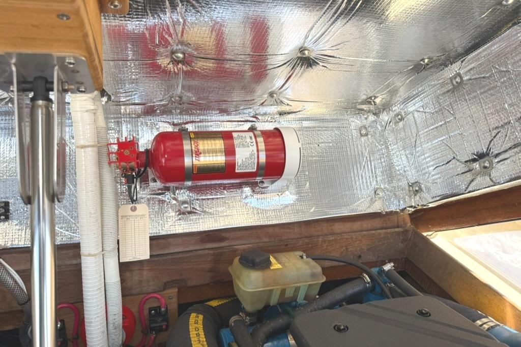Engine compartment of 1986 Dusky 26 Custom with fire extinguisher and insulation.