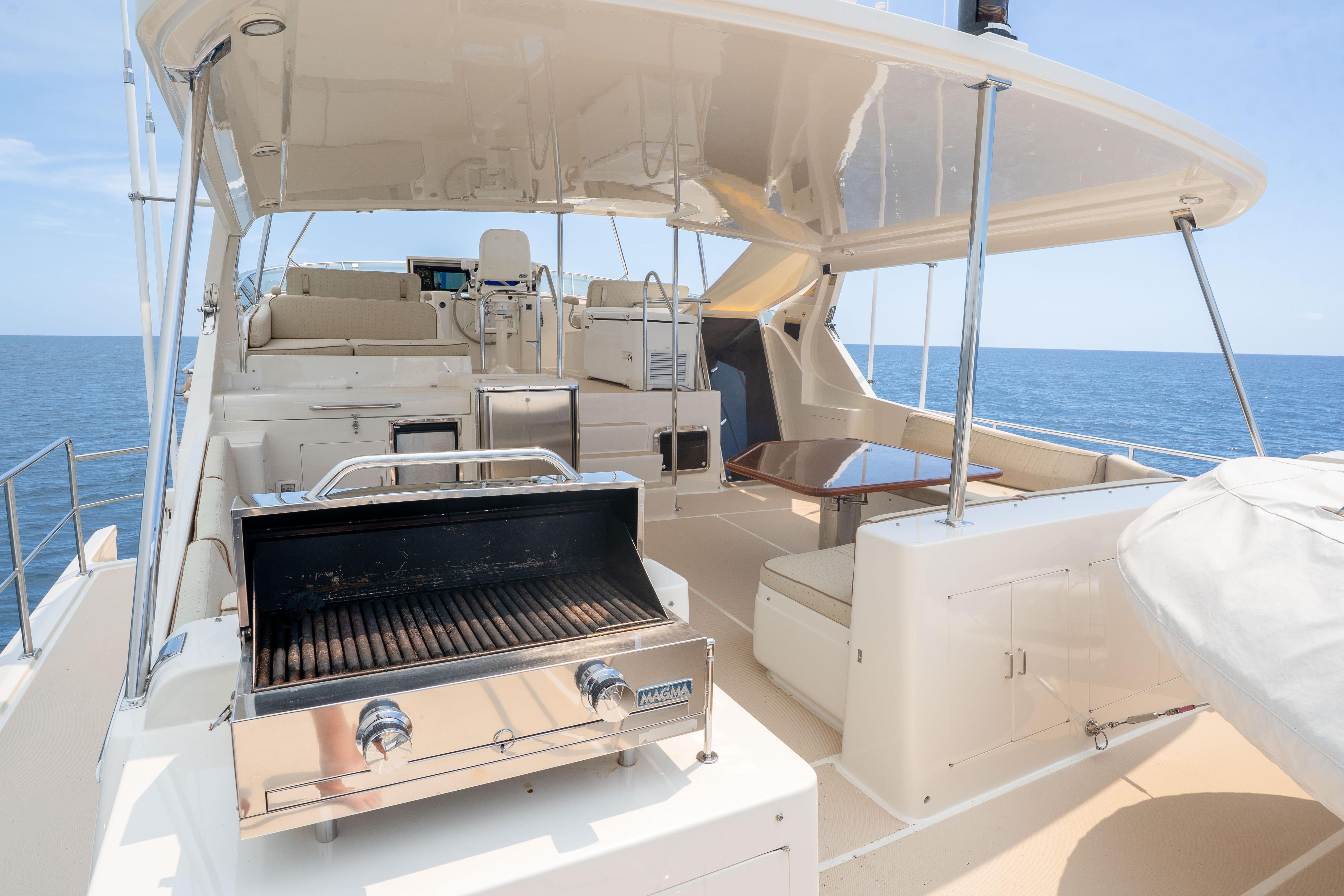 Luxurious 2006 Fleming 75 yacht deck with grill and seating, overlooking the ocean.