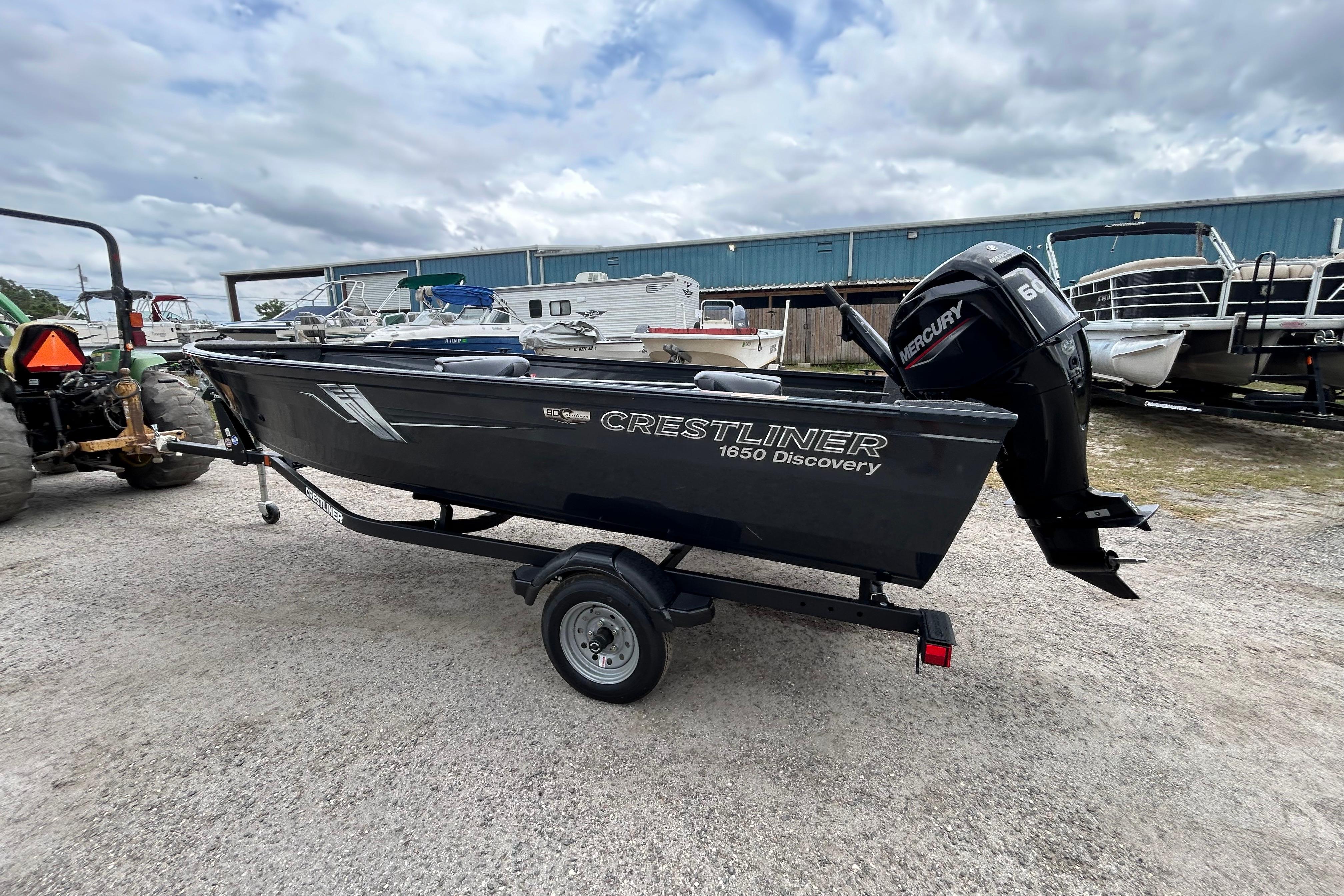 2026 Crestliner 1650 Discovery Tiller boat on trailer, parked outdoors.