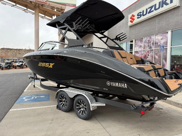 2025 Yamaha Boats 255XD in black on trailer, parked outside Suzuki dealership.