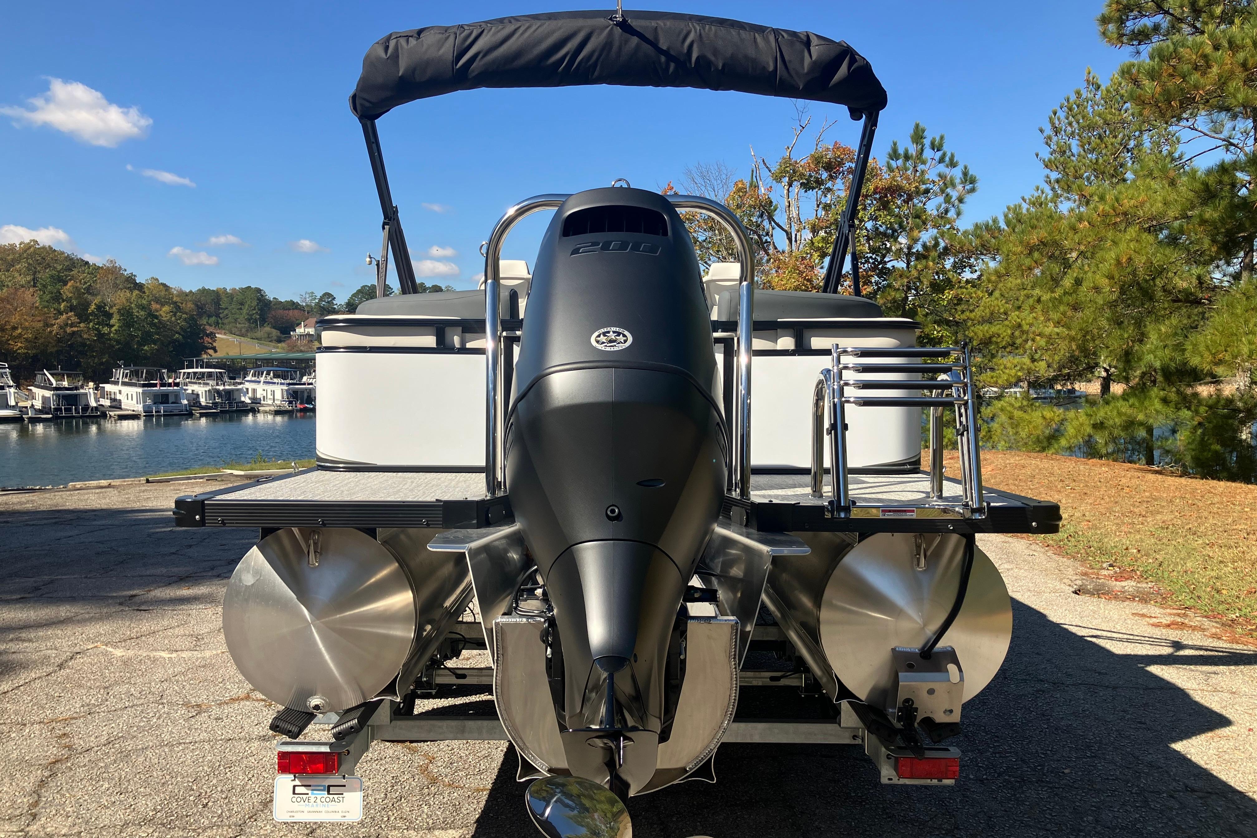 2026 Tahoe Pontoon LTZ Quad Lounger with powerful outboard motor, docked by a scenic lake.