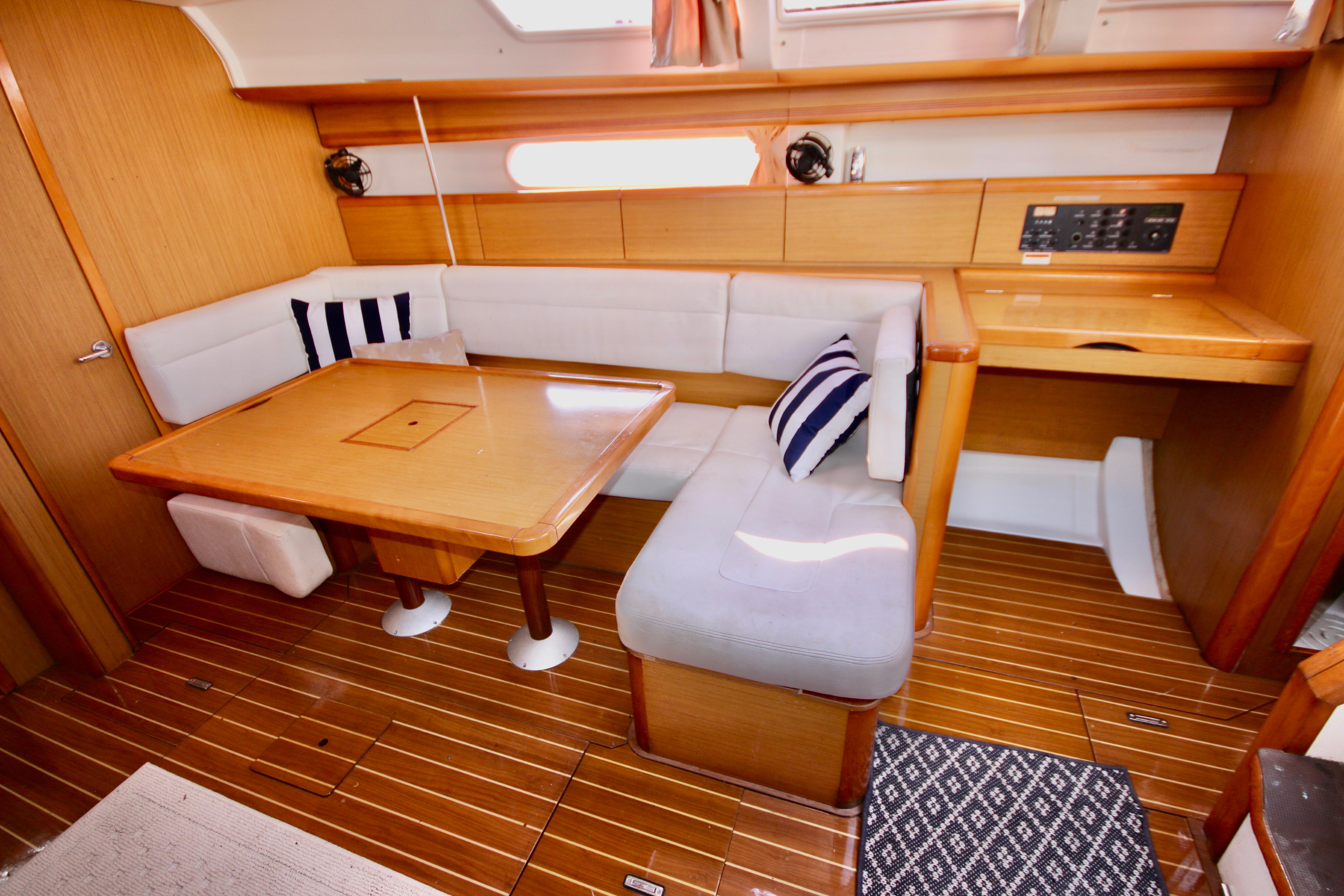 Interior of 2009 Jeanneau Sun Odyssey 44i yacht with wooden flooring and cozy seating area.