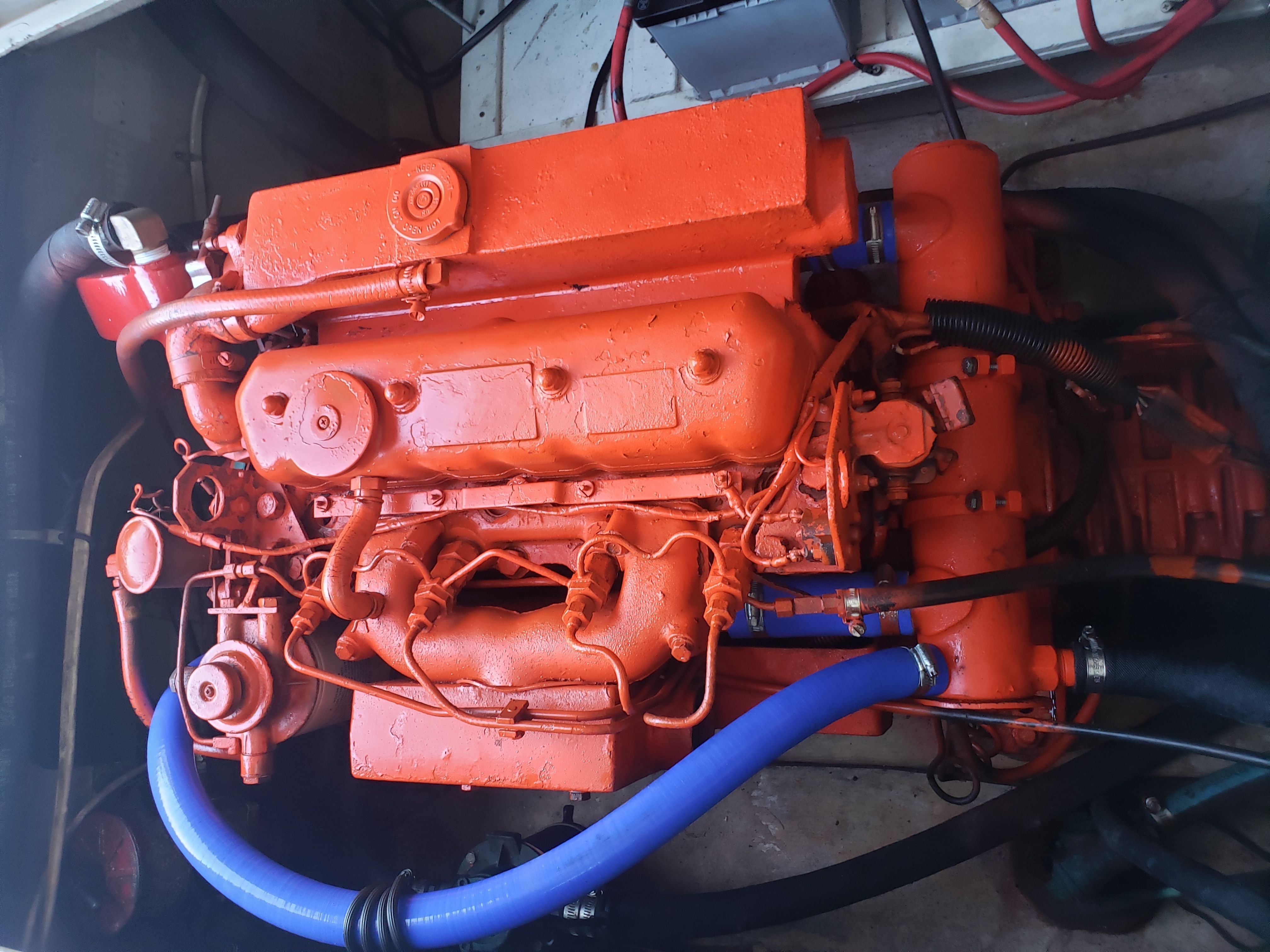An orange engine in a boat, surrounded by blue and black hoses.