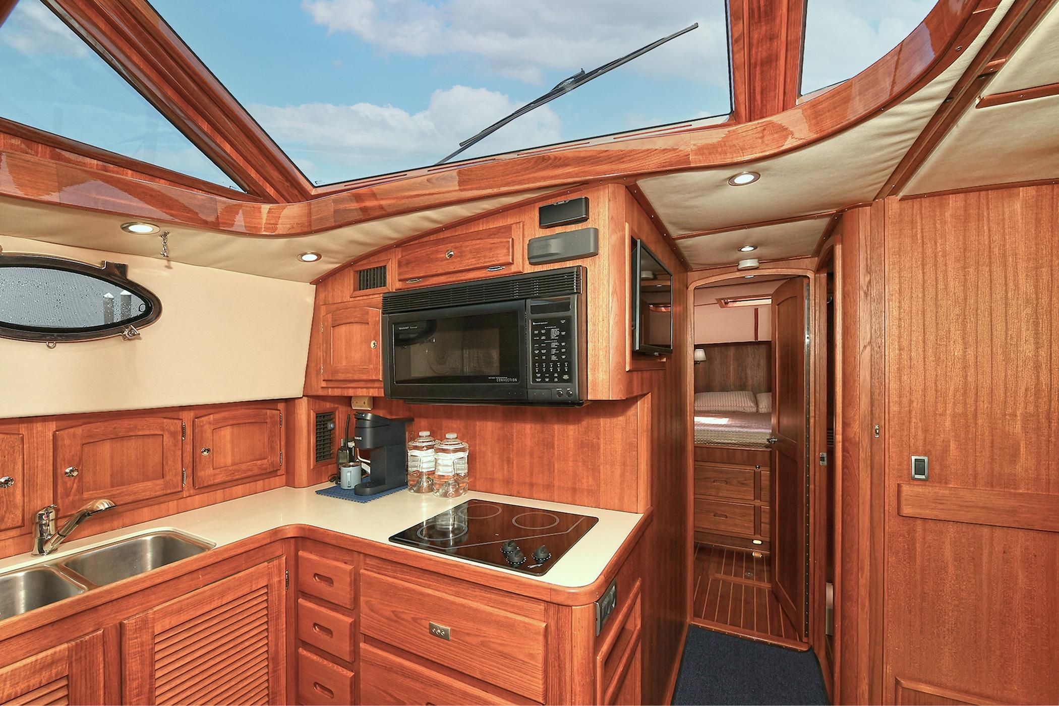 Luxurious 2005 San Juan Downeast Express yacht interior with wood cabinetry and modern kitchen amenities.