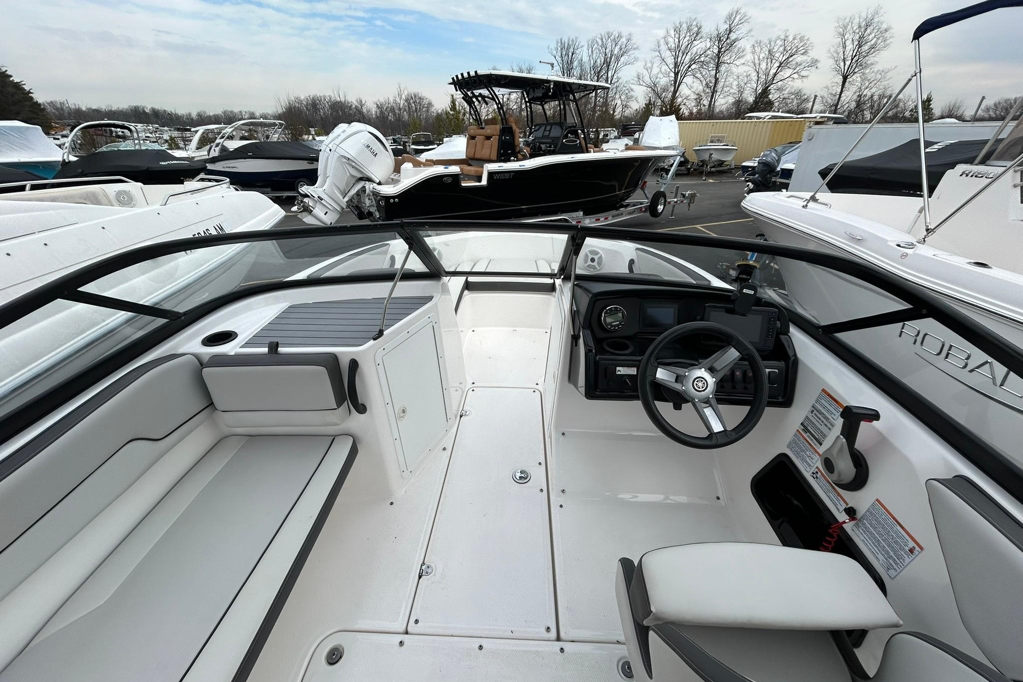 2019 Yamaha Boats AR190 interior with steering wheel and seating, parked among other boats.